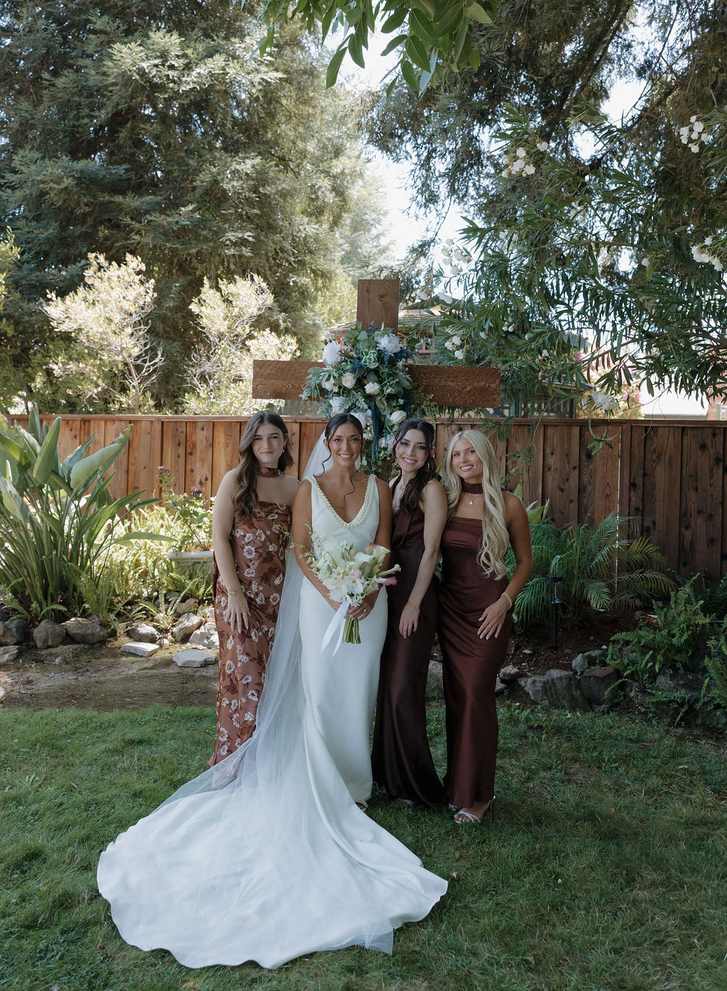 Bridal party photo with bride smiling with bridesmaids in brown bridesmaid dresses