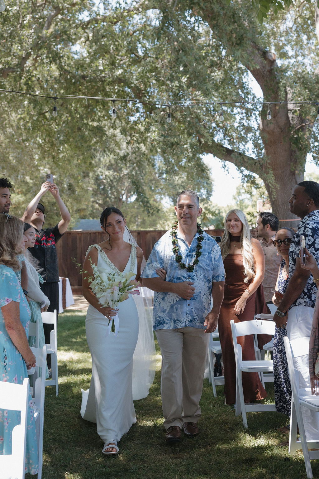 Father walking bride down the aisle while she smiles at her husband