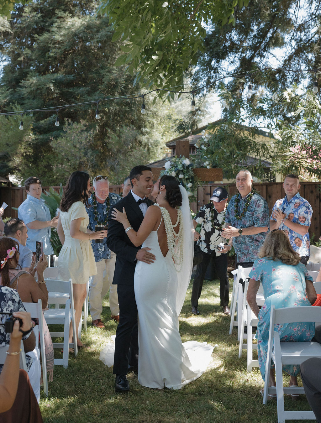 Bride and groom pausing to kiss while walking down the aisle after their wedding ceremony