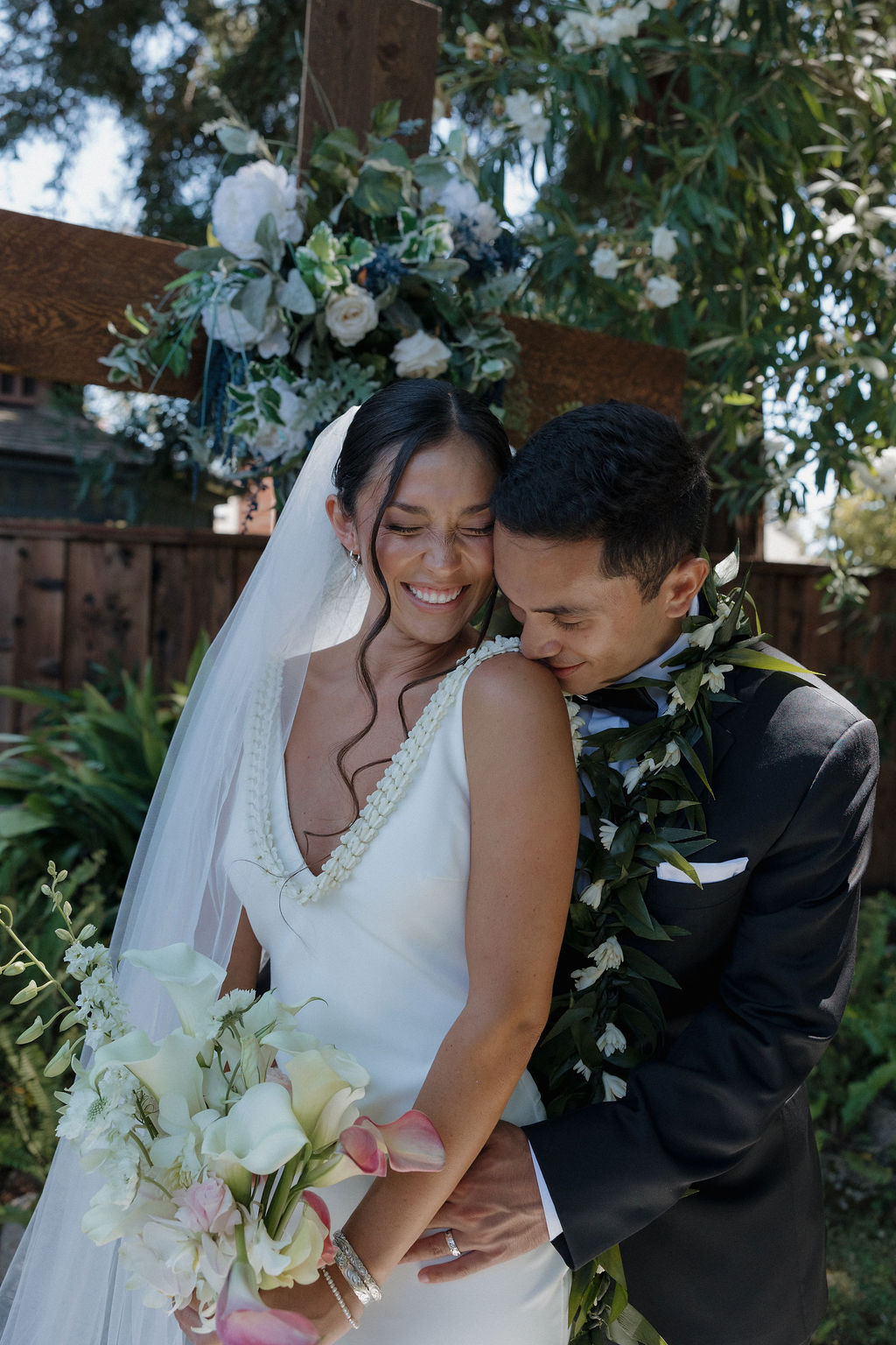 Groom kissing his bride on the shoulder while she's laughing