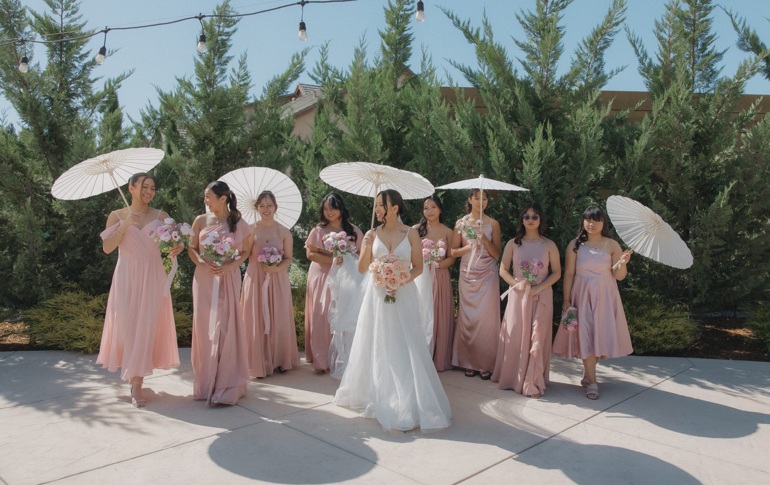 A candid bridesmaid photo idea with bridesmaids in pink dresses holding parasols