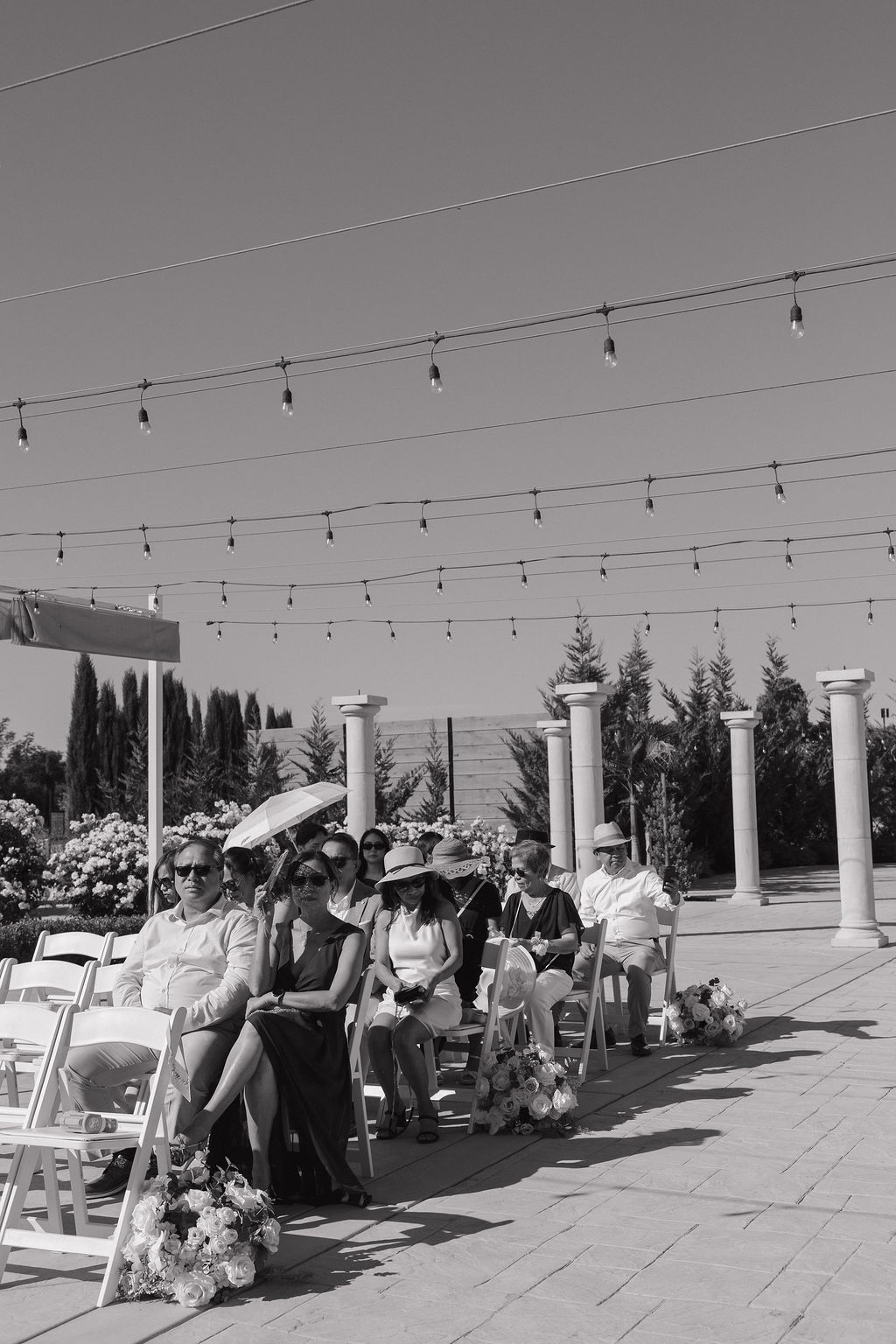 Black and white candid photo of wedding guests watching the wedding ceremony