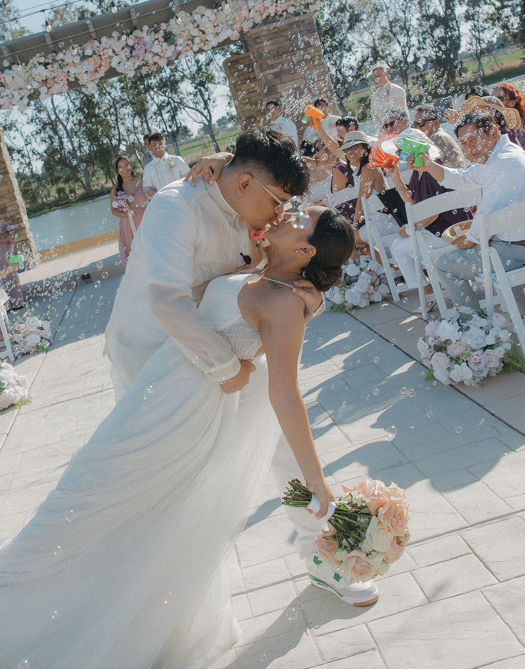 Bride and groom kissing while recessing down the aisle, surrounded by a bubble sendoff
