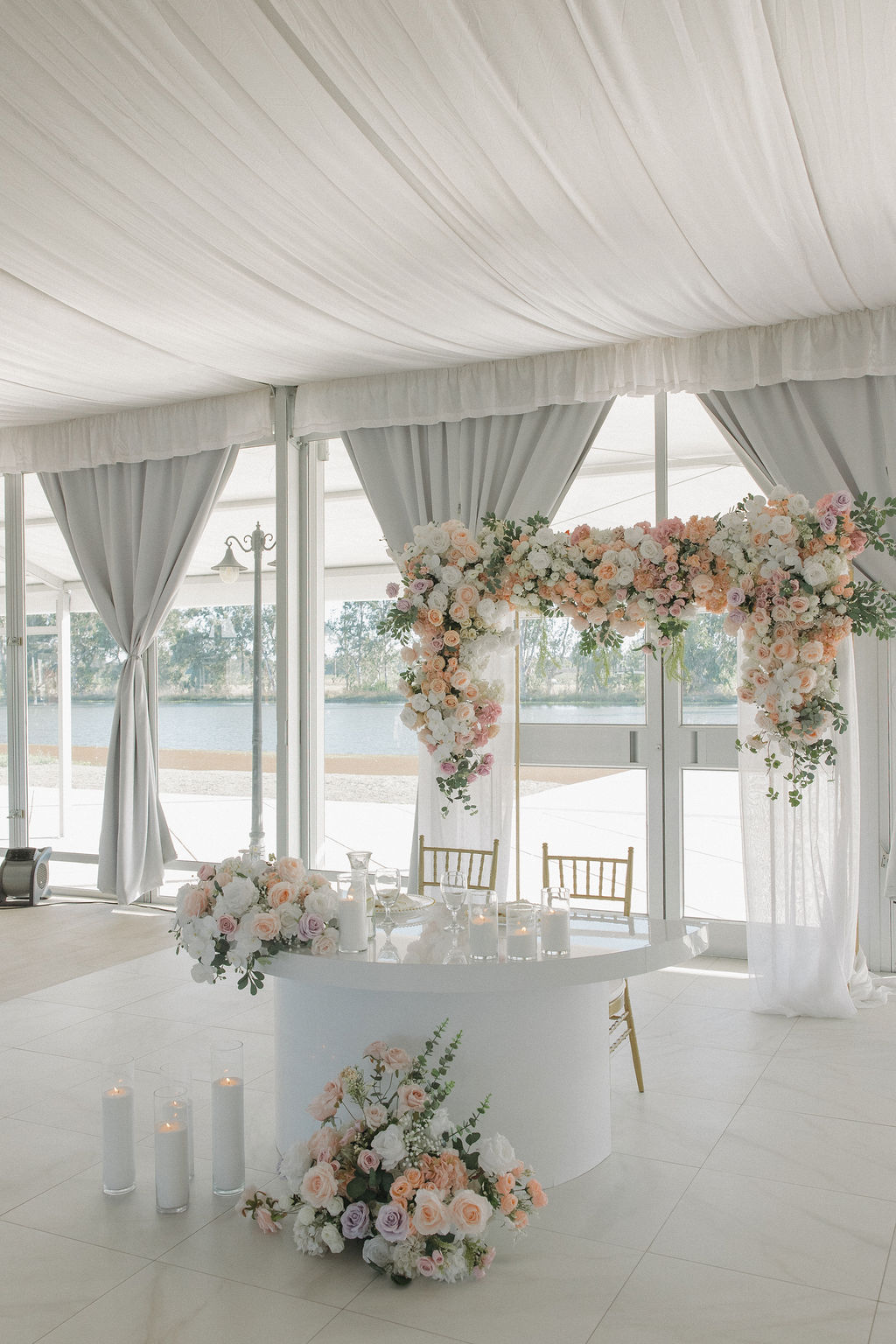 Sweetheart table setup with pastel pink flowers under a tent