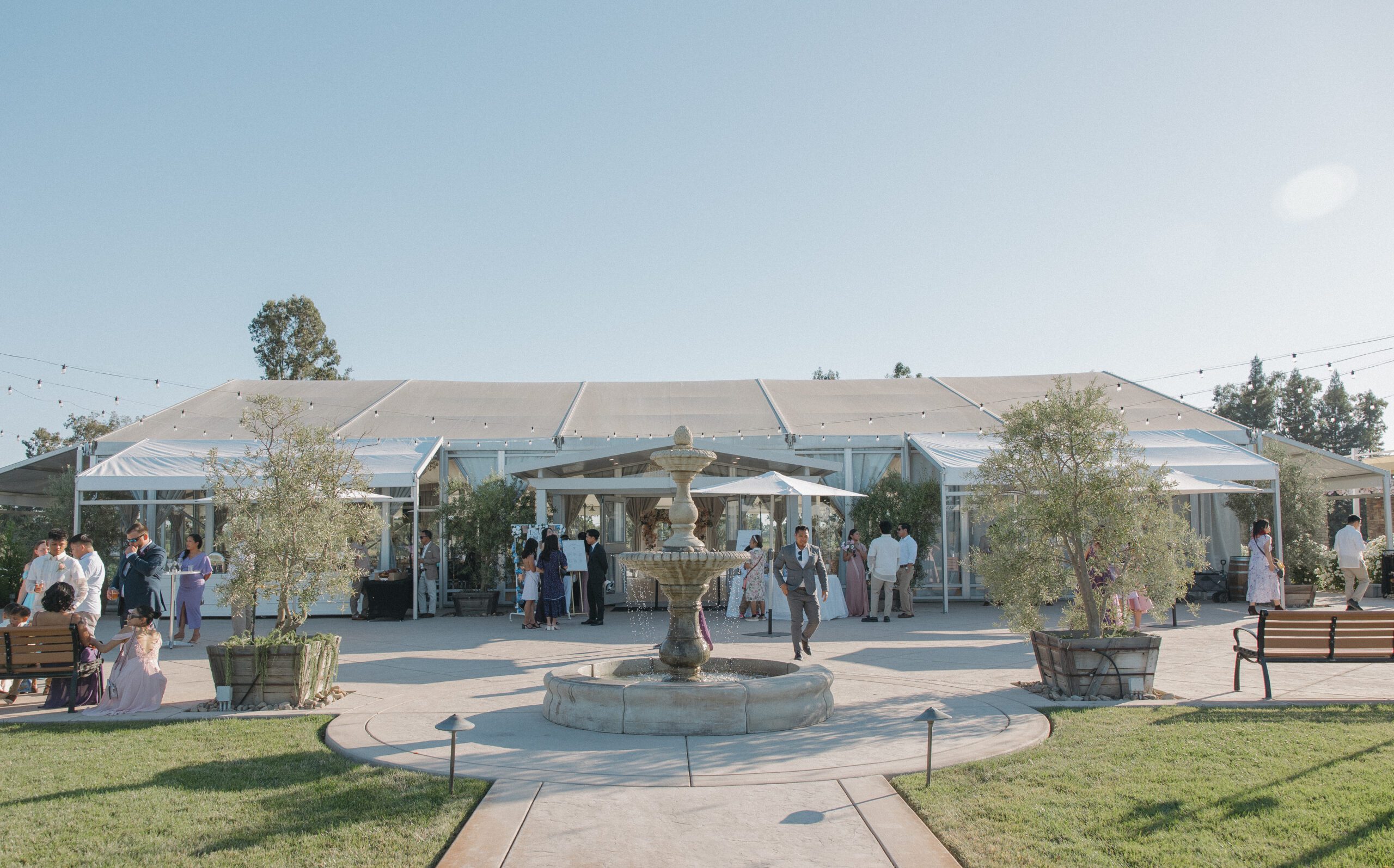 Guests at a wedding outside of the Marquee at Lakeview Estates, with a fountain in the middle 