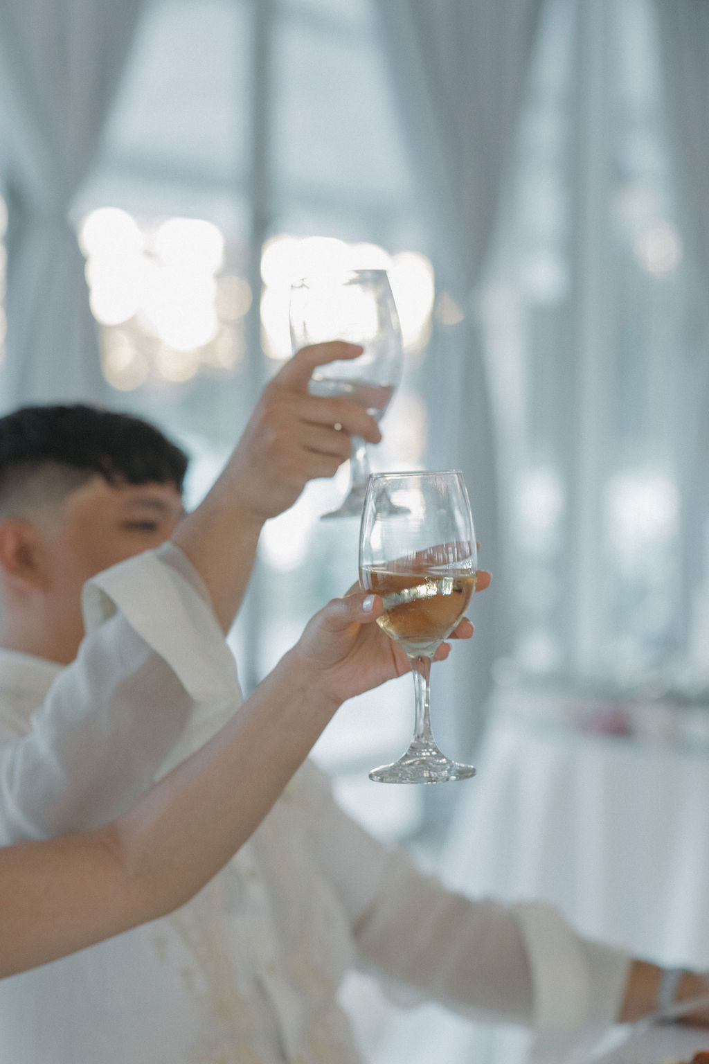 Candid wedding photo of bride and groom holding up glasses for a toast