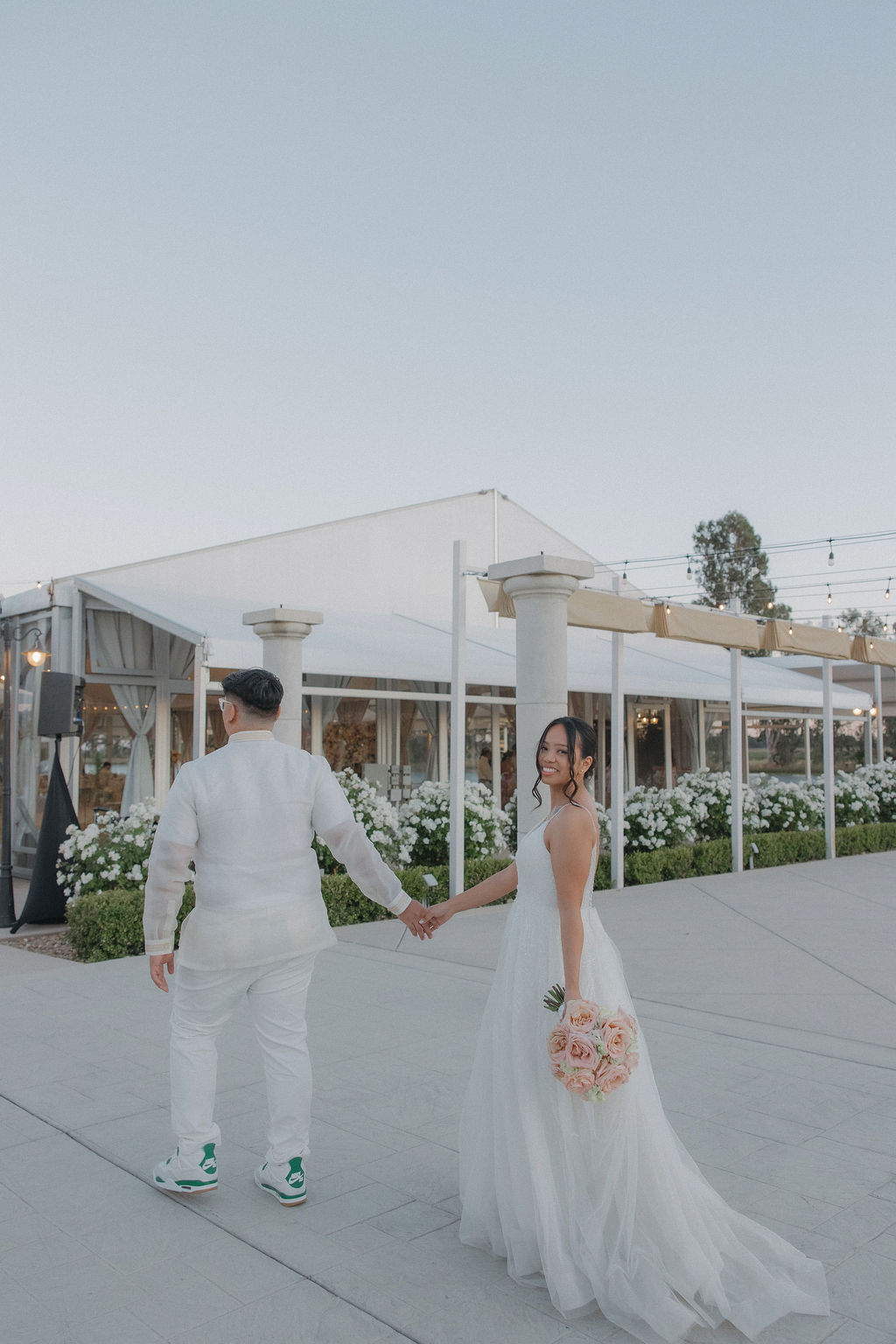 Groom walking the bride towards the marquee at Lakeview estates, an outdoor tent with tall windows