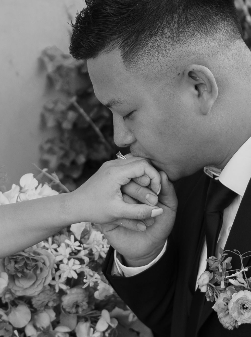 Groom kissing bride's hand in black and white wedding photo