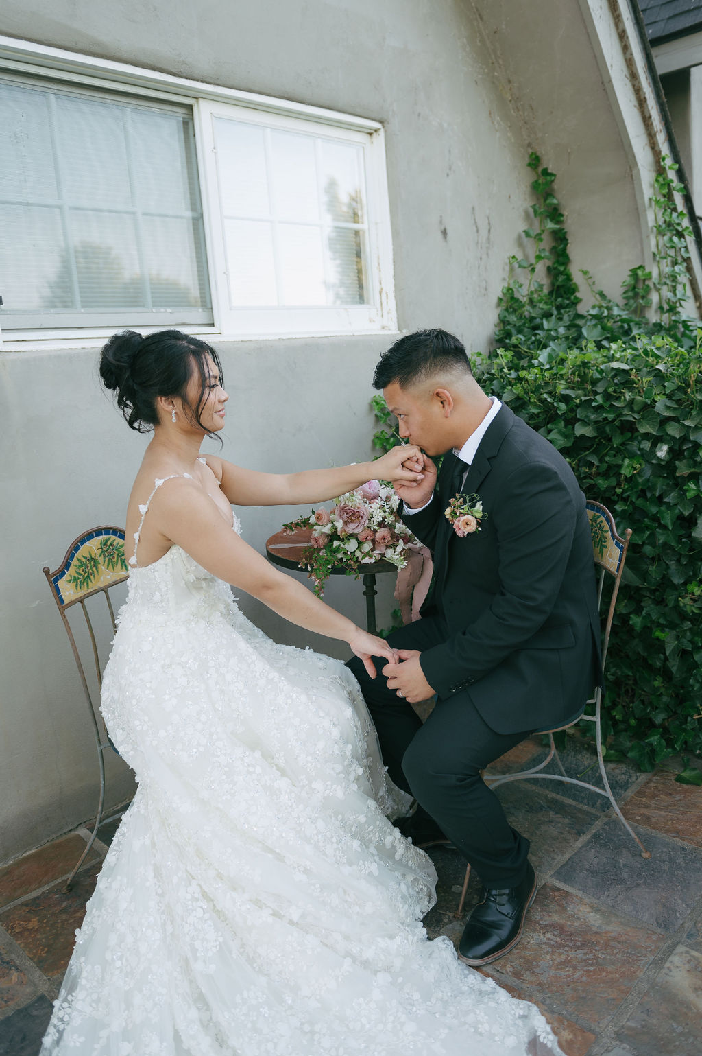 Groom kissing bride's hand at a small table