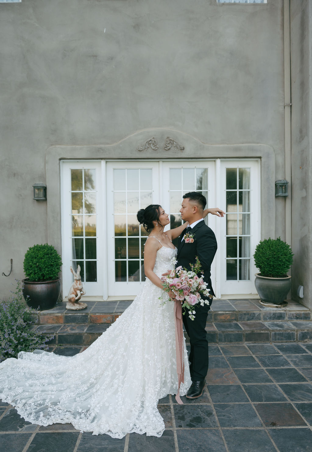 Bride and groom smiling at each other in front of wedding venue's French doors