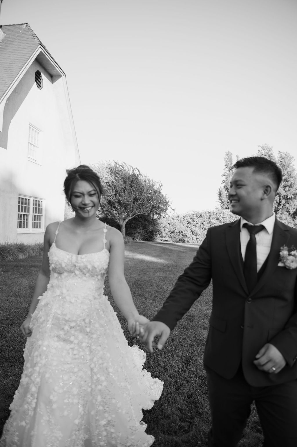 Black and white photo of bride and groom running towards camera
