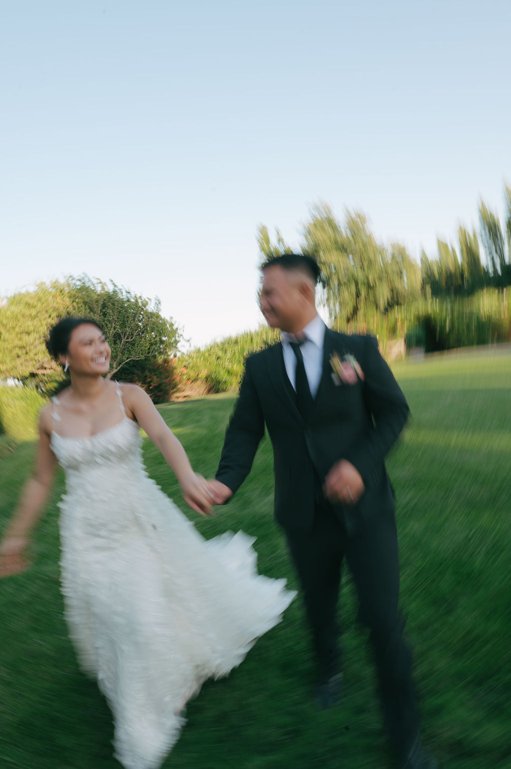 Blurry photo of bride and groom running on a lawn