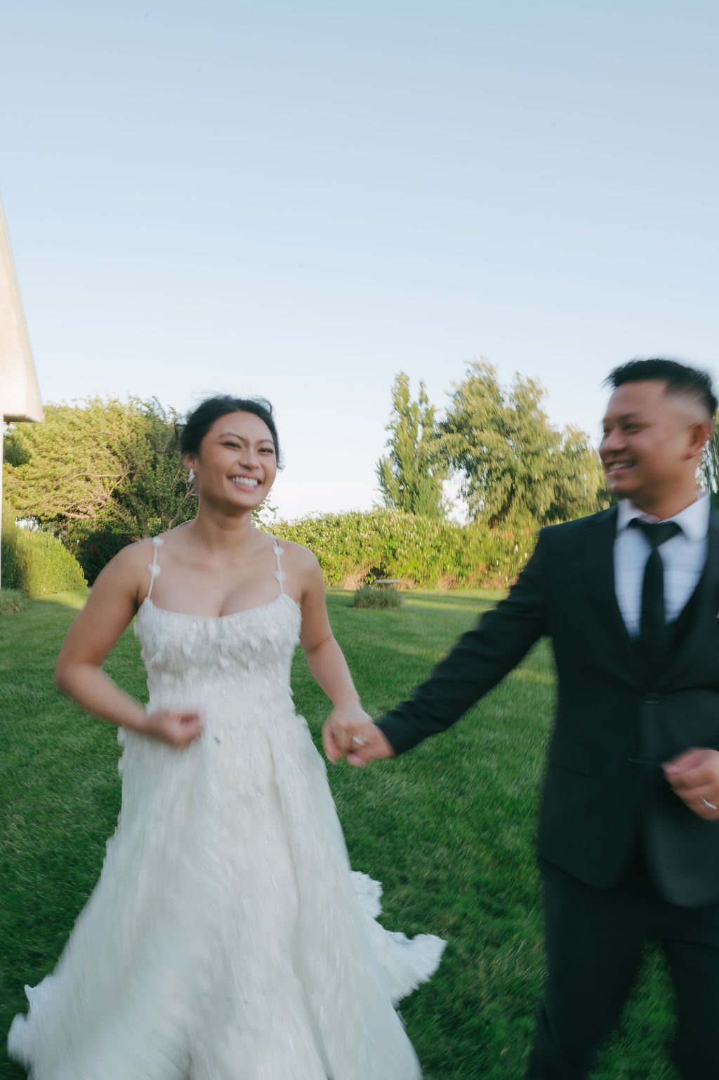 Bride and groom running on a lawn