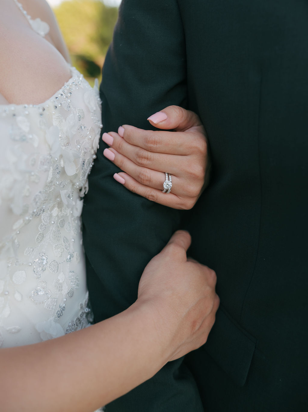 Bride hugging grooms arm for a wedding ring photo