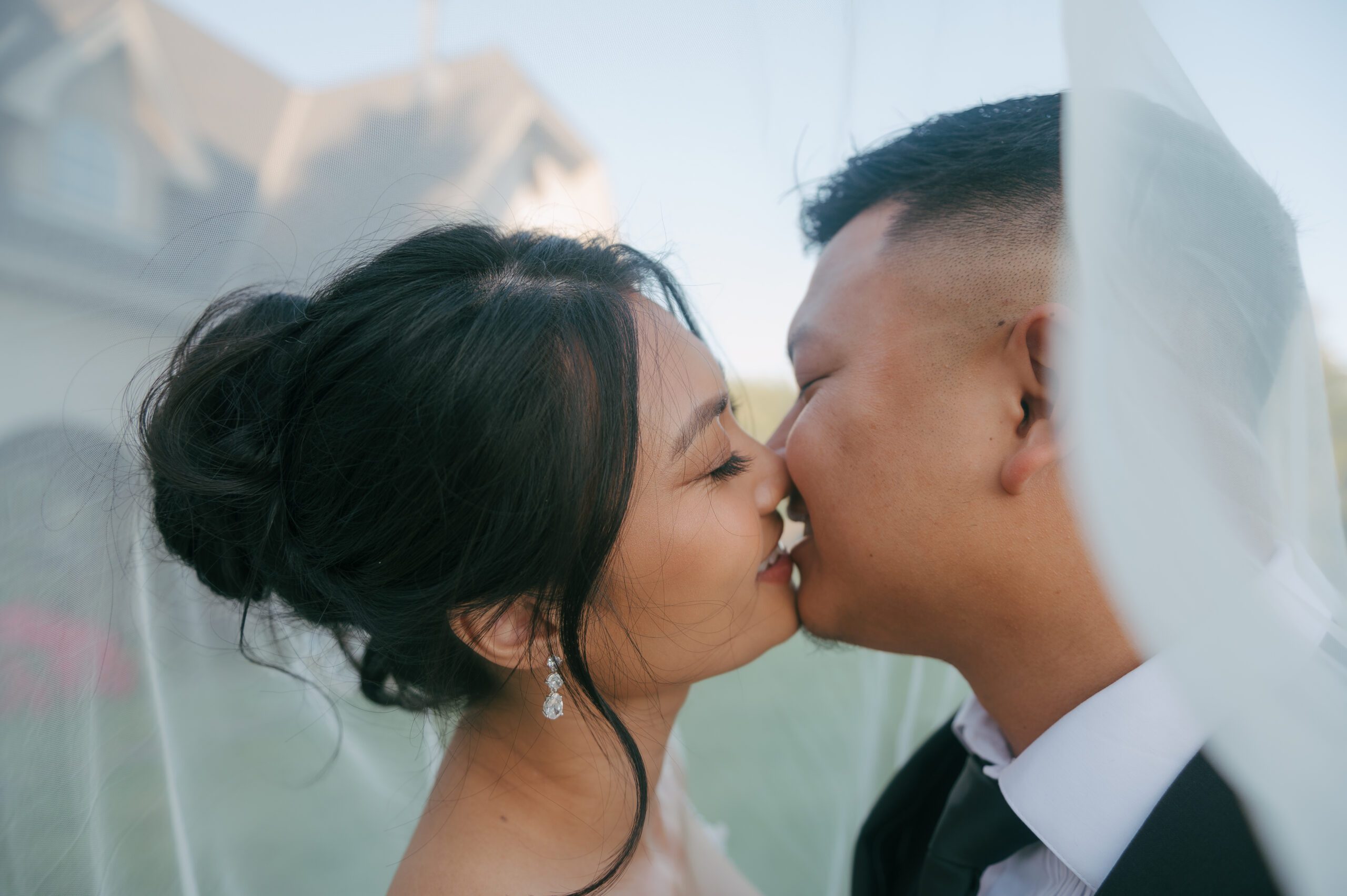 Bride and groom leaning in for a kiss under bride's veil