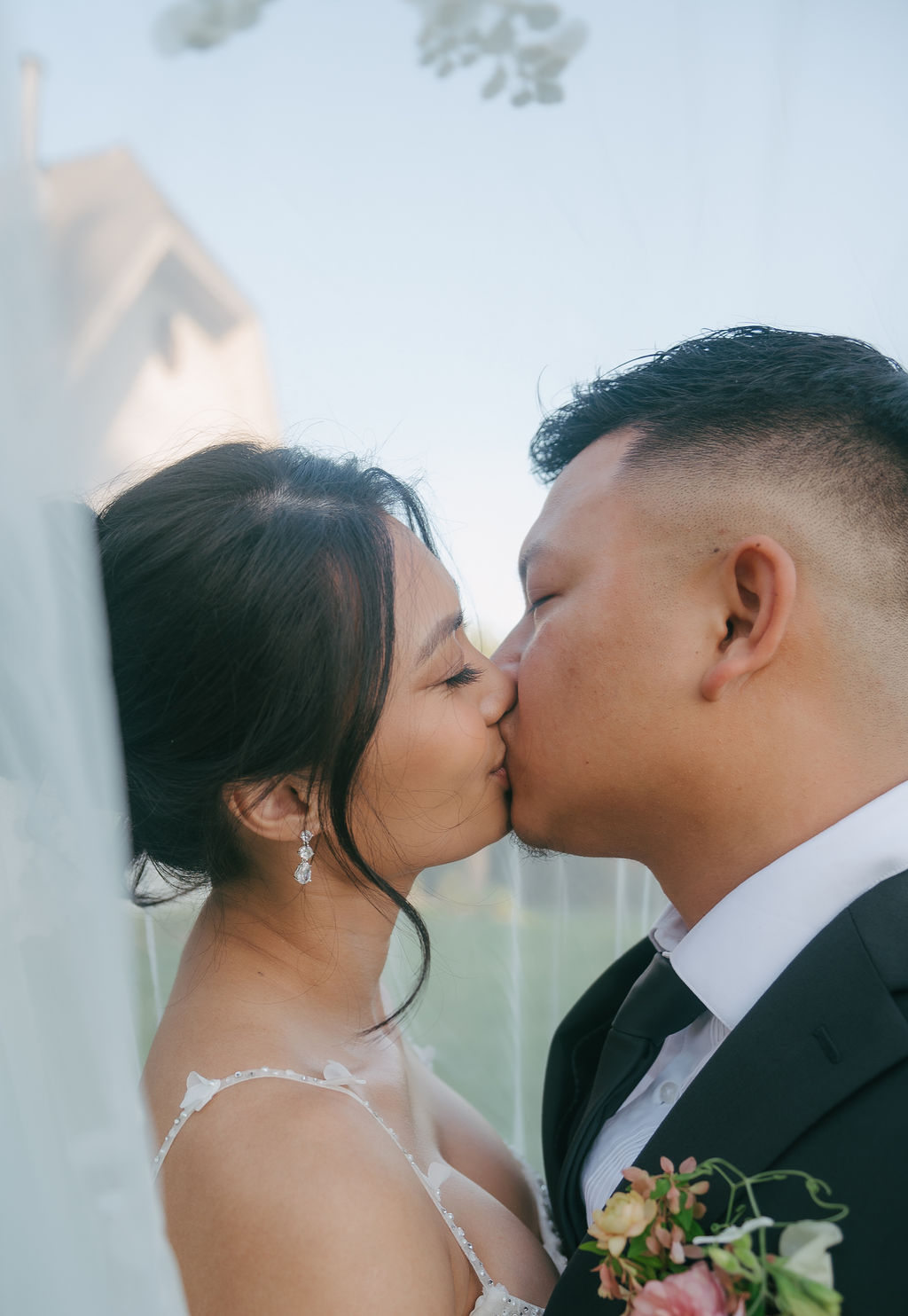 Bride and groom kissing under a veil