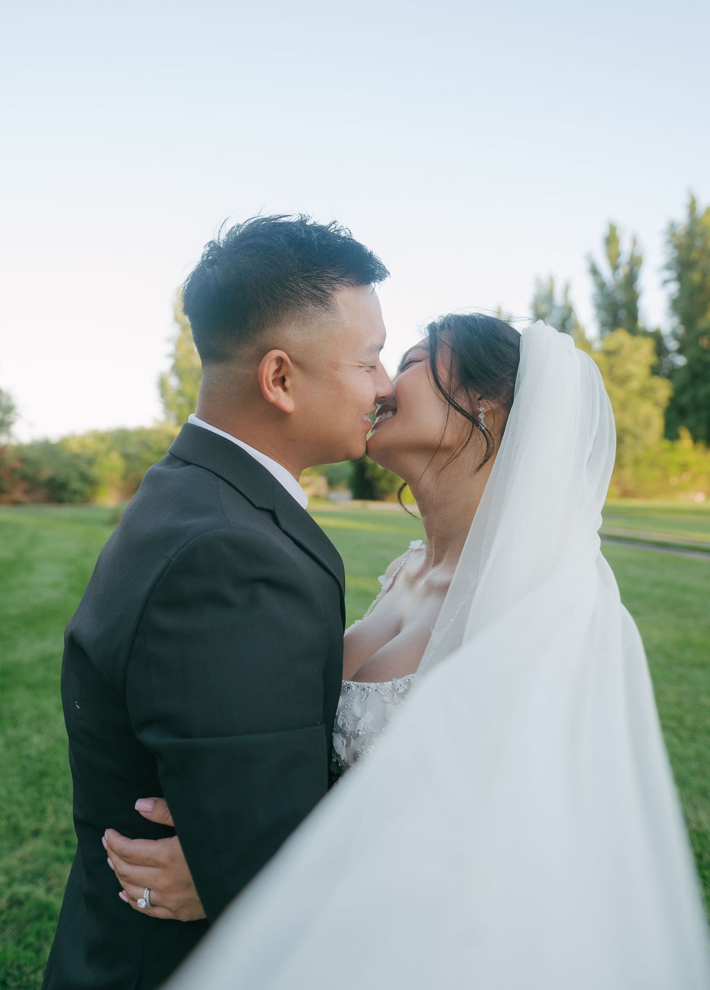Bride and groom leaning in for a kiss with bride's veil in front of the camera, as wedding photoshoot inspo