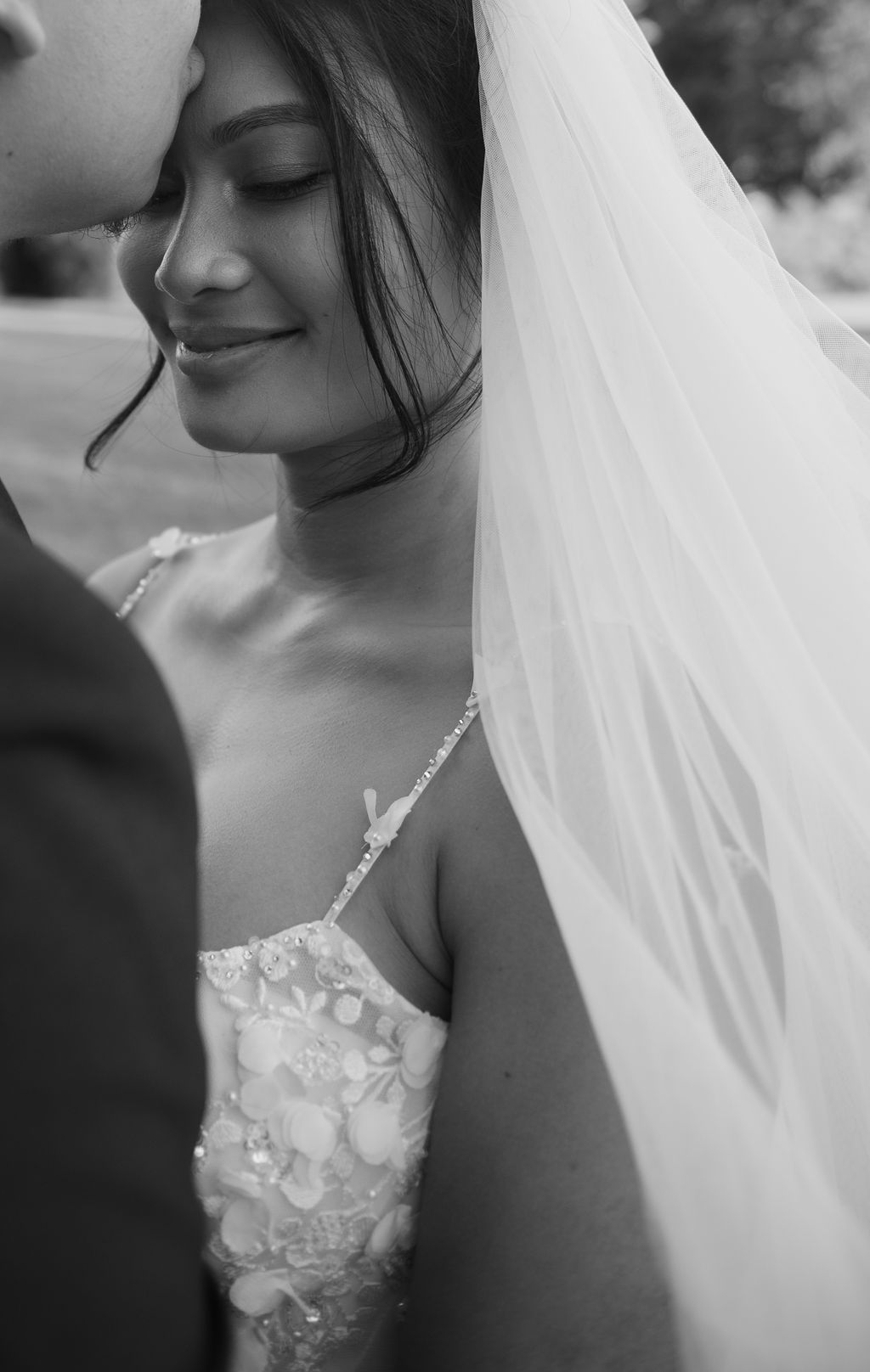 Black and white photo of groom kissing bride's forehead