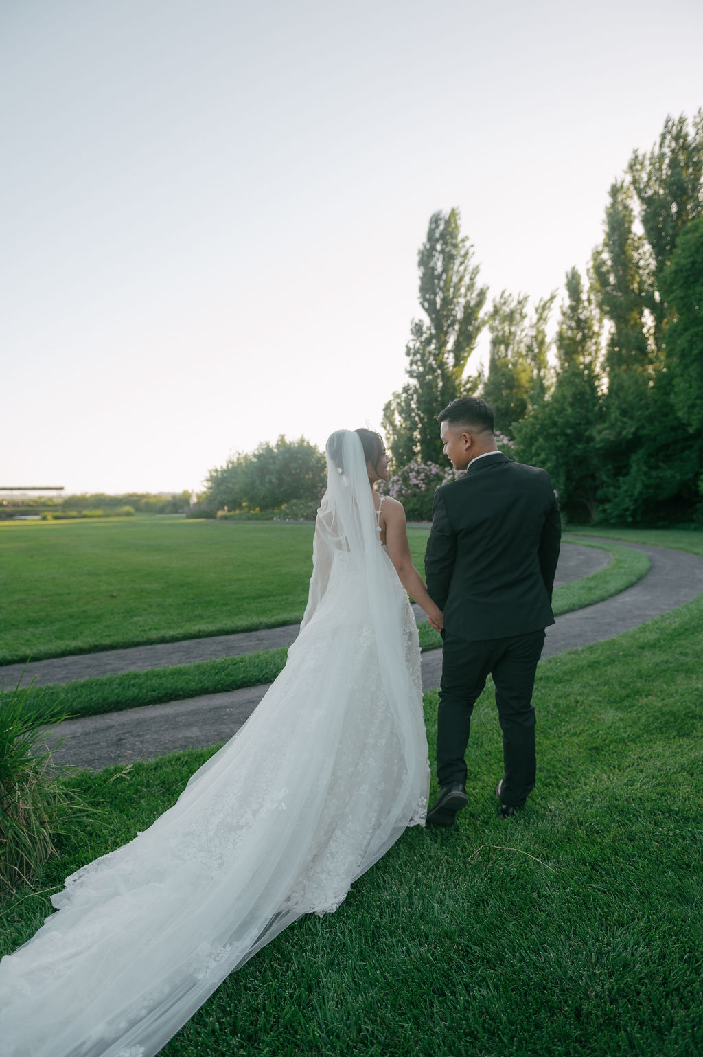 Wedding portraits of bride and groom holding hands walking down trail