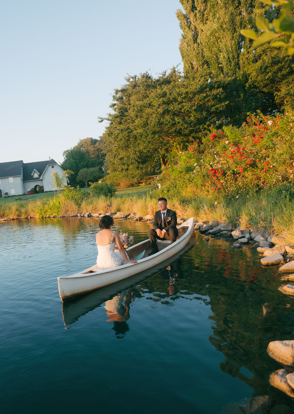 Bride and groom sitting in a row boat on a pond