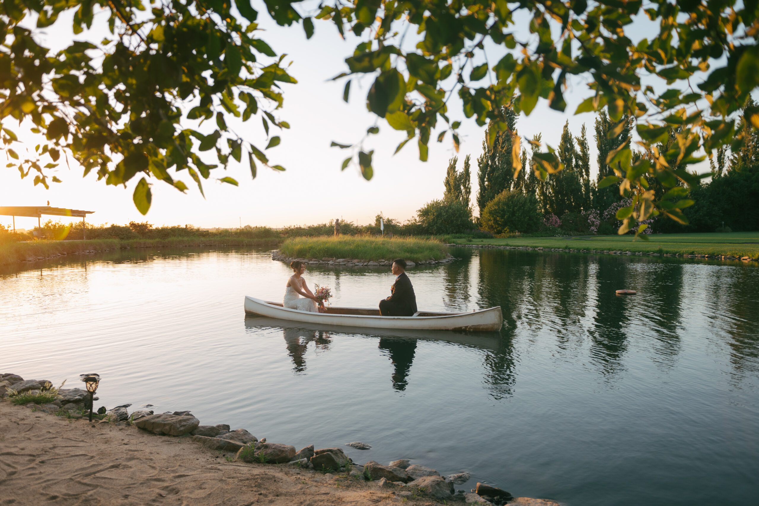 Bride and groom in a row boat on a pond as wedding portraits
