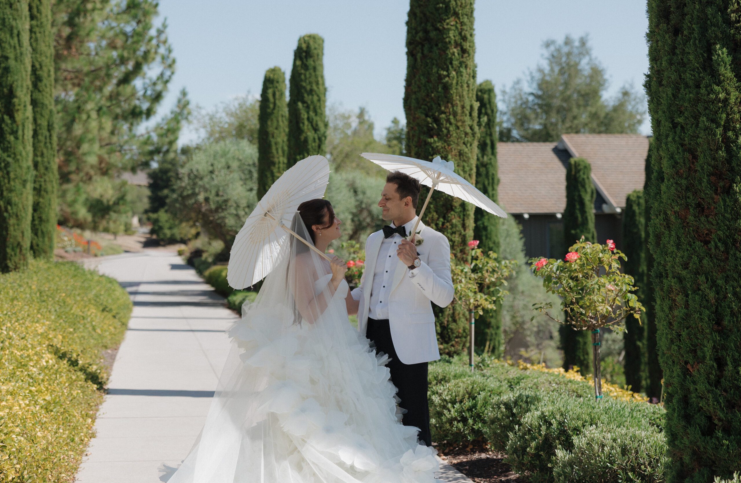 Bride and groom posing with parasols for wedding photos