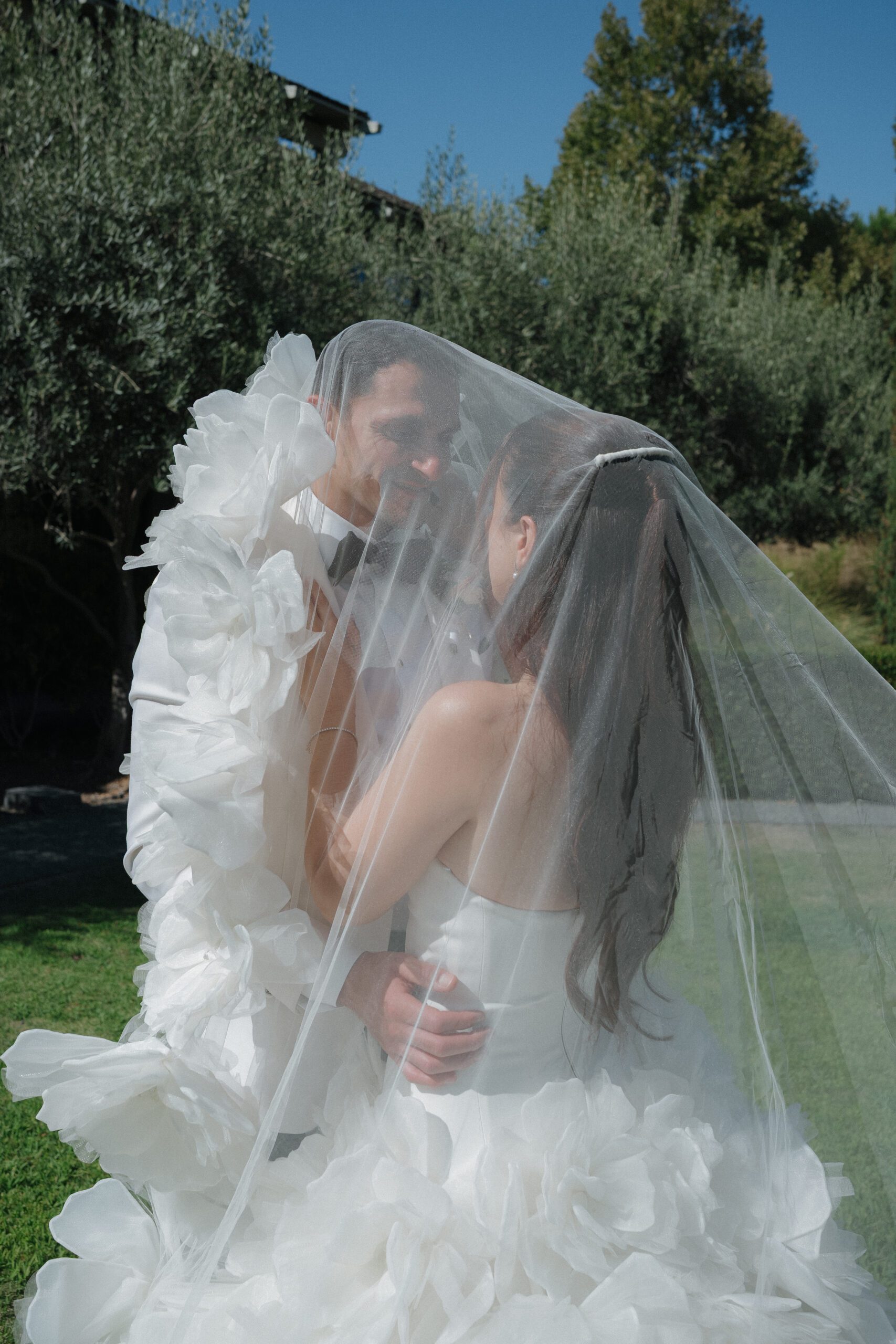 Bride and groom taking pictures underneath blusher veil