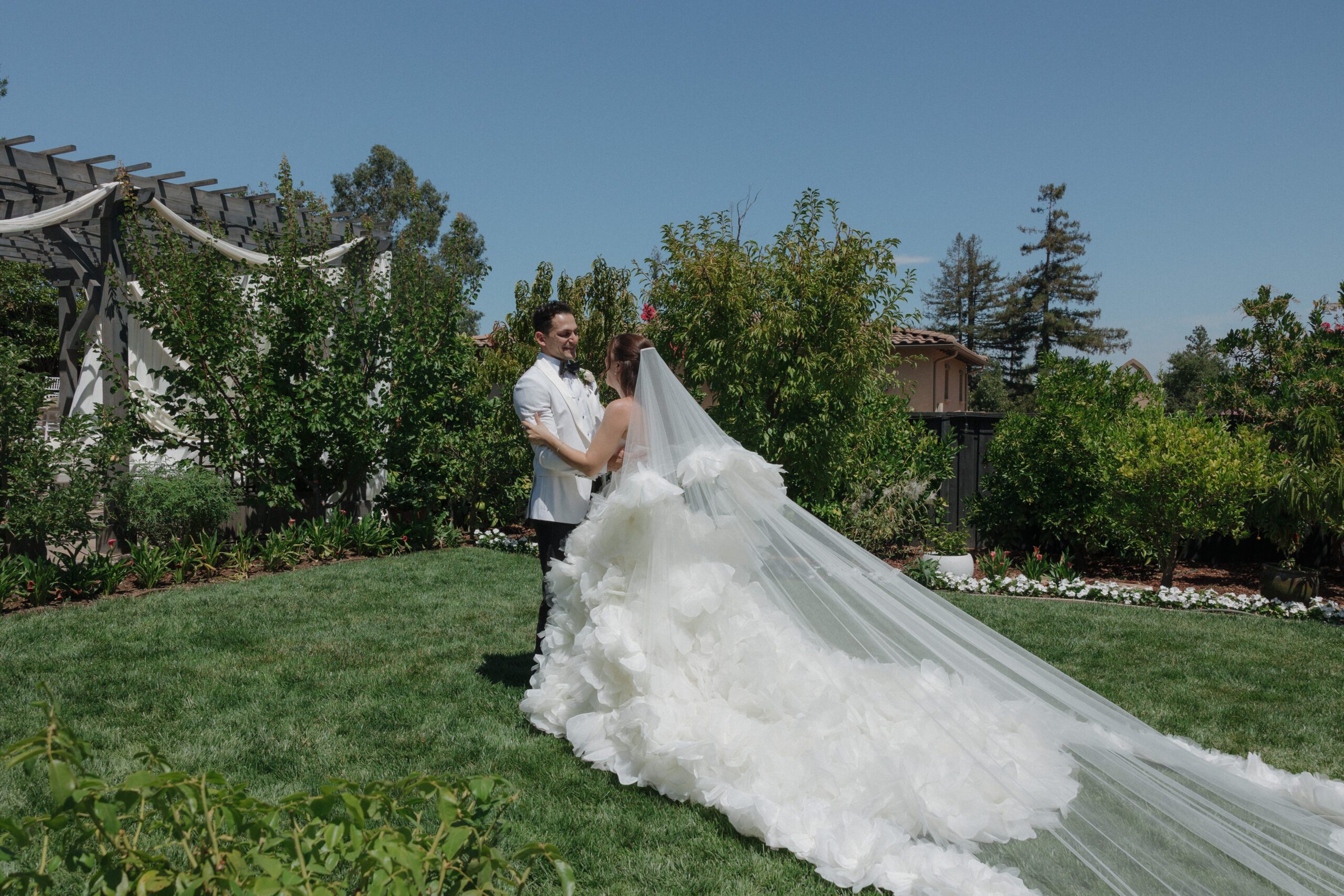 Bride and groom photo with statement veil trailing behind bride