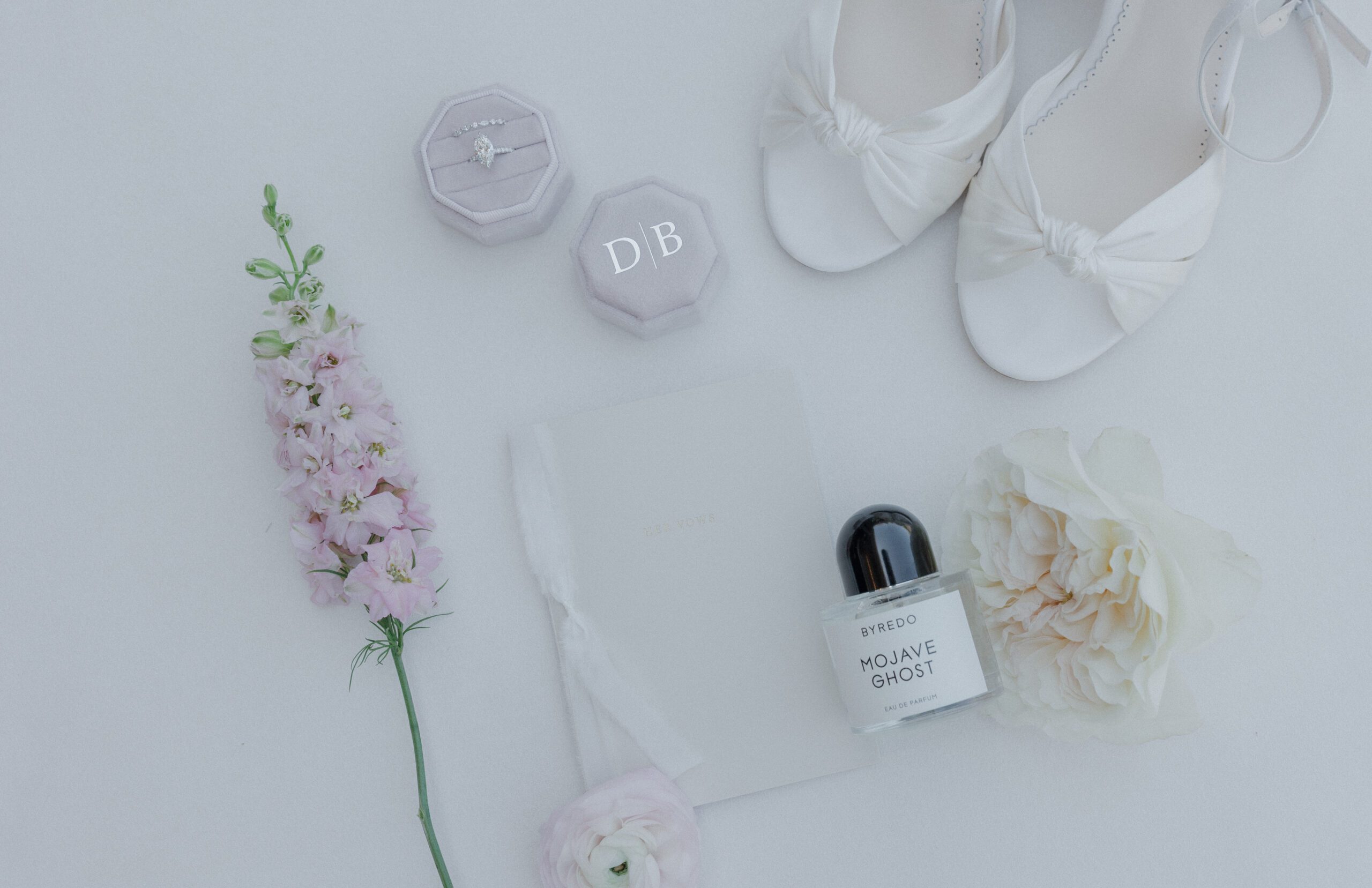 A wedding flatly with wedding rings, wedding shoes, wedding perfume, and wedding flowers