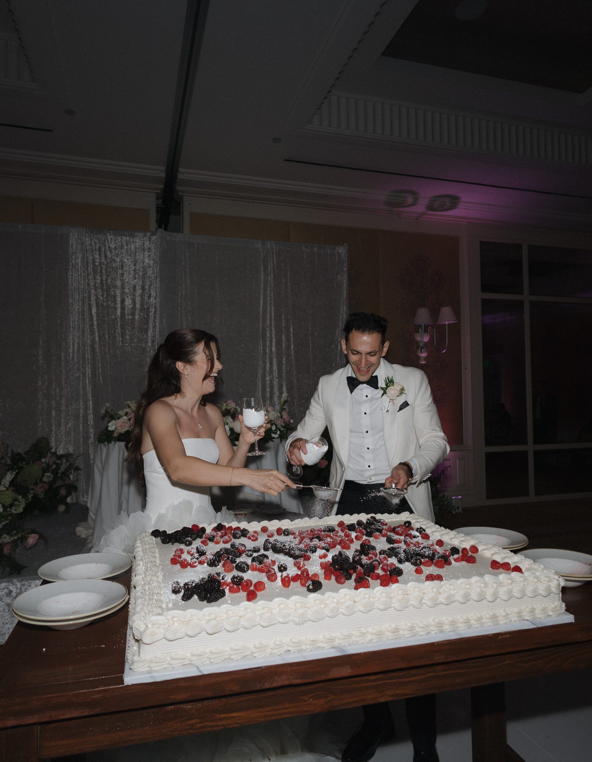 Bride and groom putting powdered sugar on their sheet cake