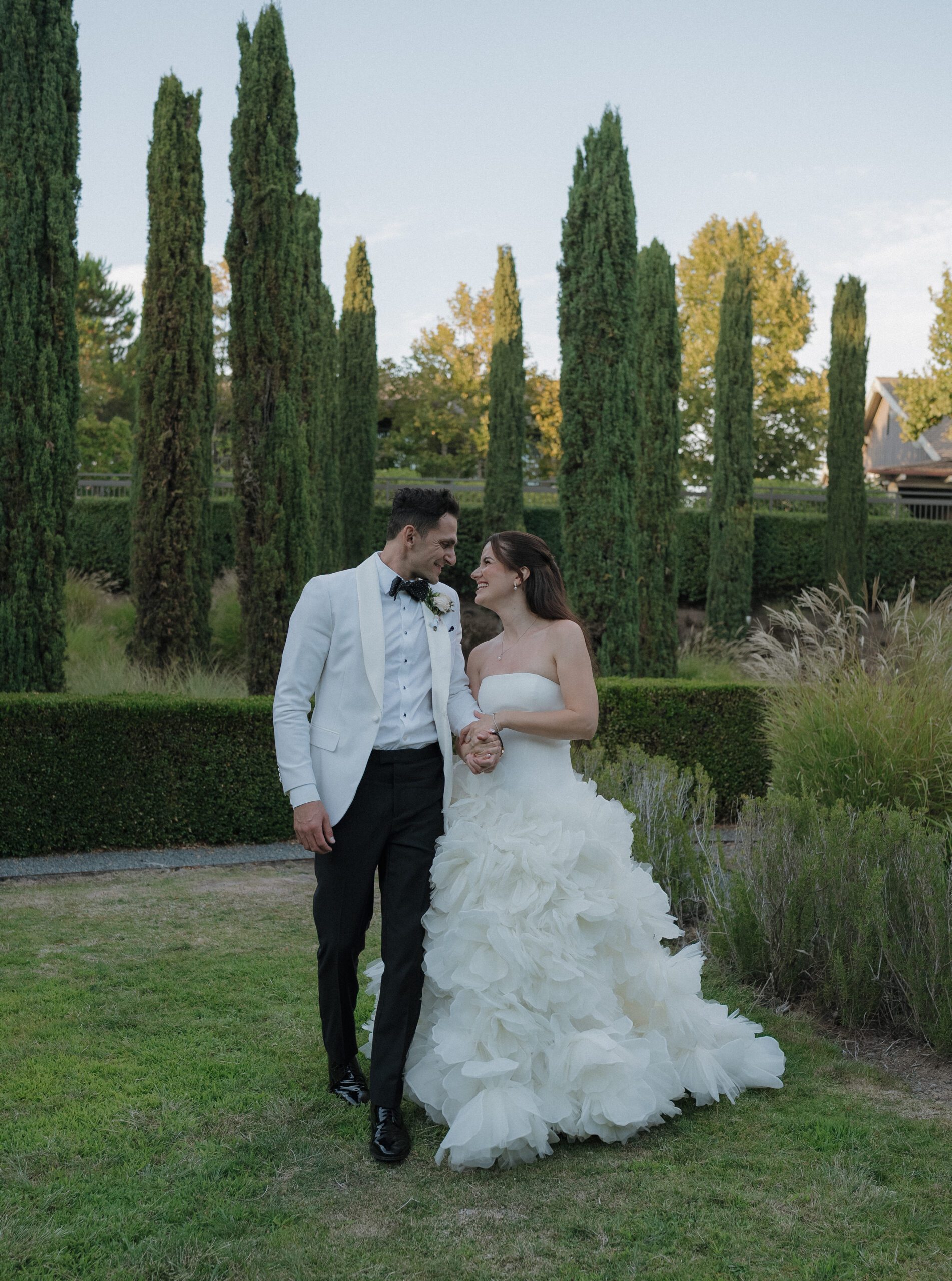 Bride and groom looking at each other laughing while walking