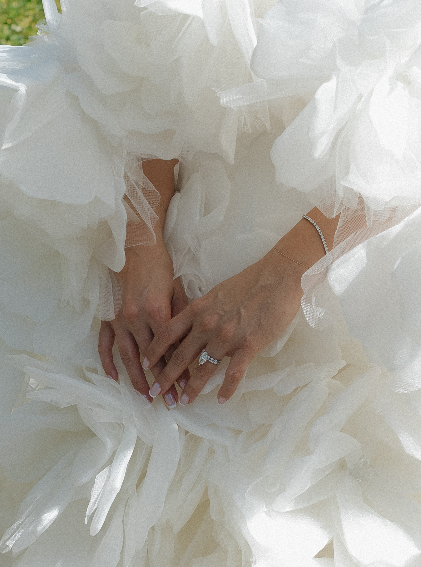 An up close photo of bride's wedding dress with 3d florals and her ring