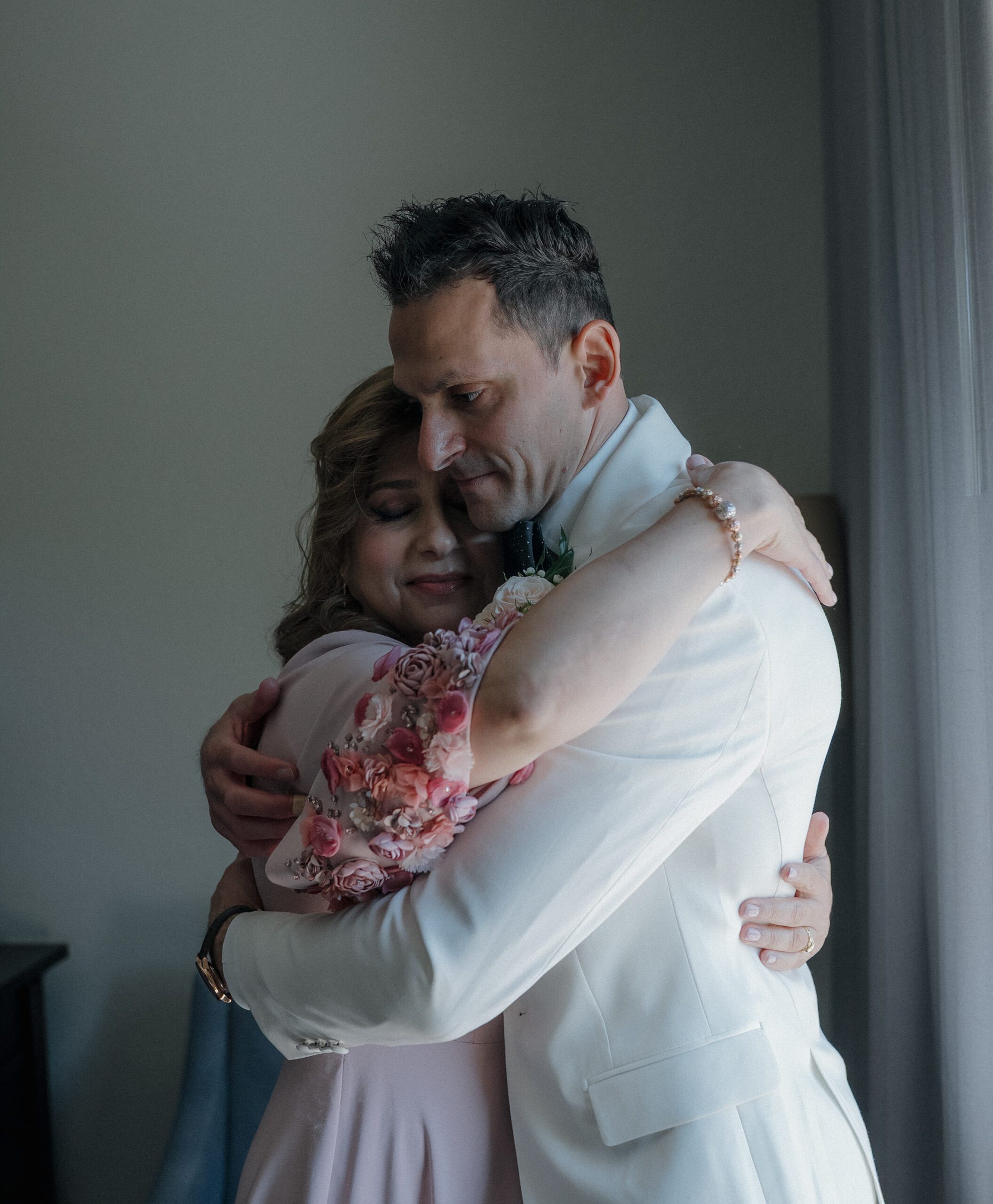 Groom and mother of the groom hugging in candid wedding photos