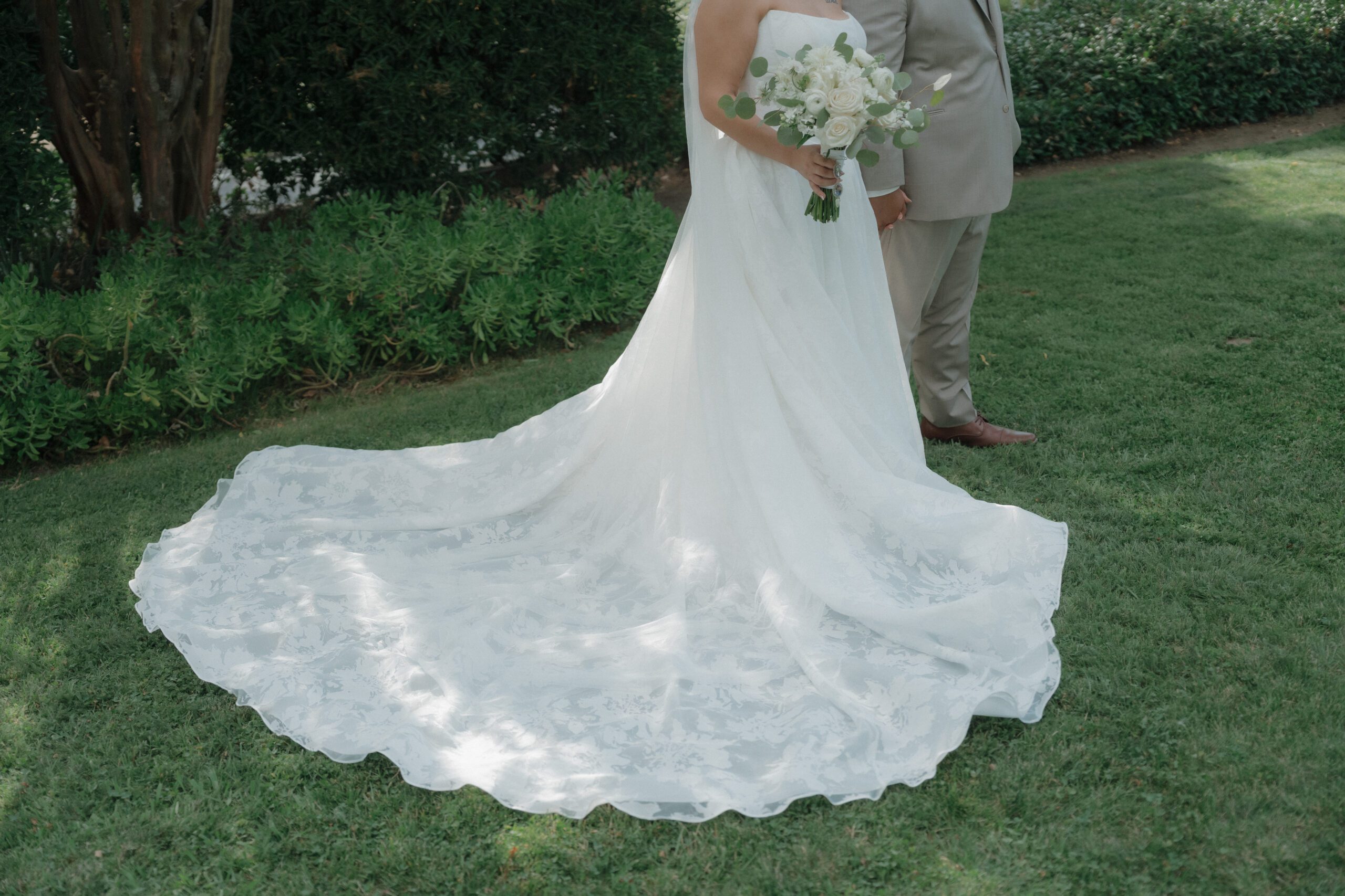 Editorial wedding photo of bride and groom walking across lawn