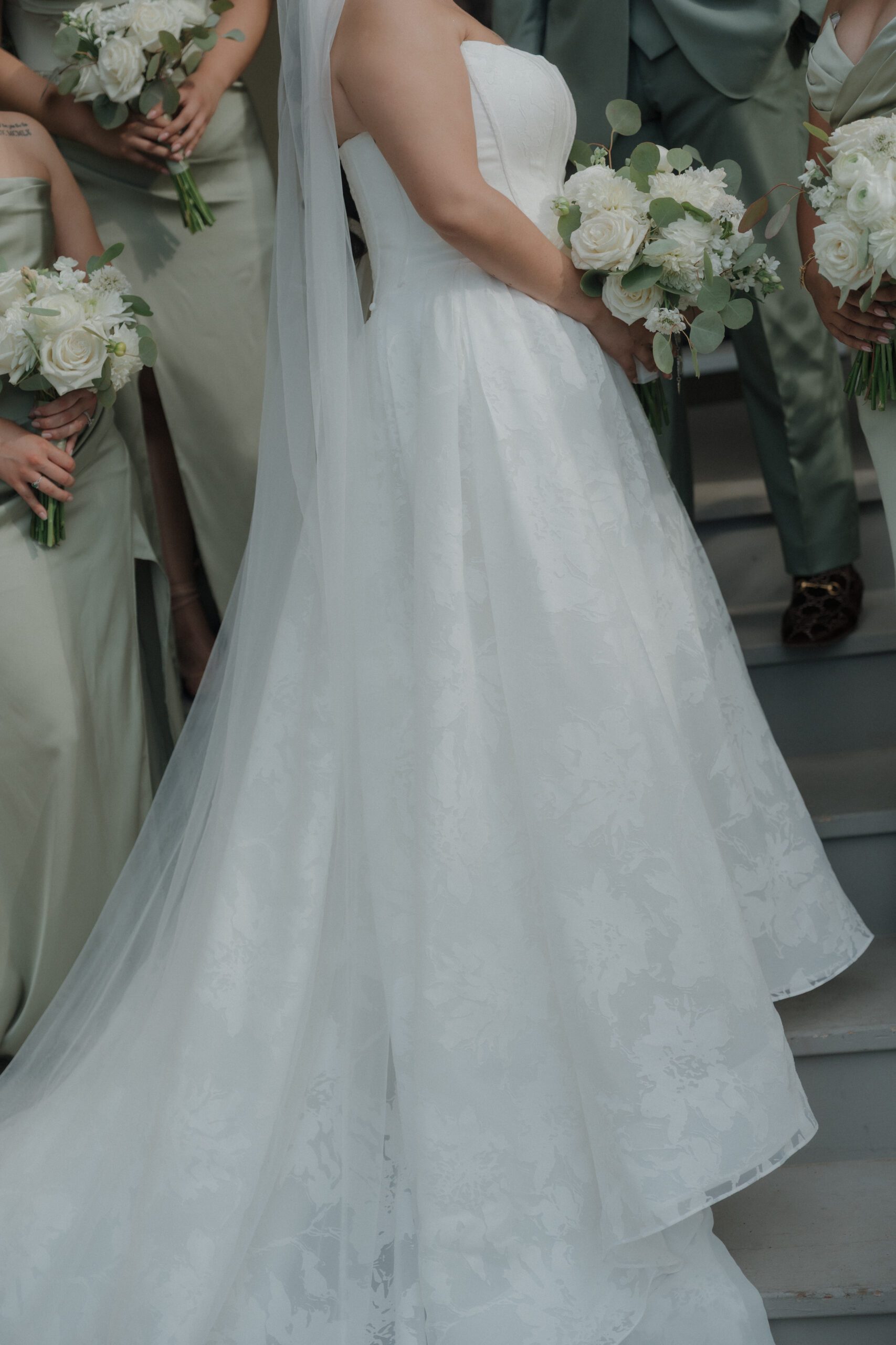 Up close details of bride's wedding dress and sage green bridesmaid dresses