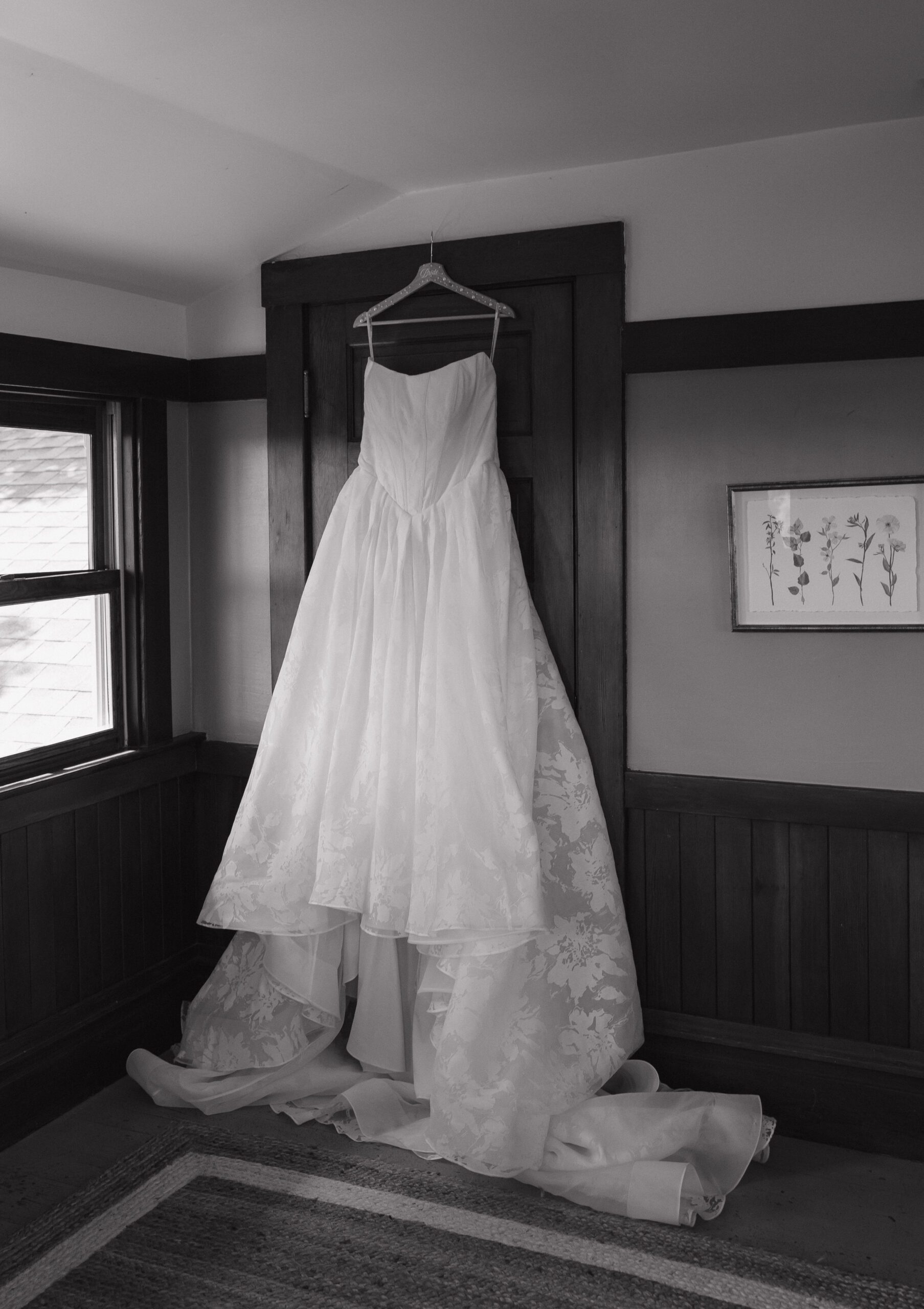 Bride's simple elegant wedding dress handing up in bridal getting ready suite