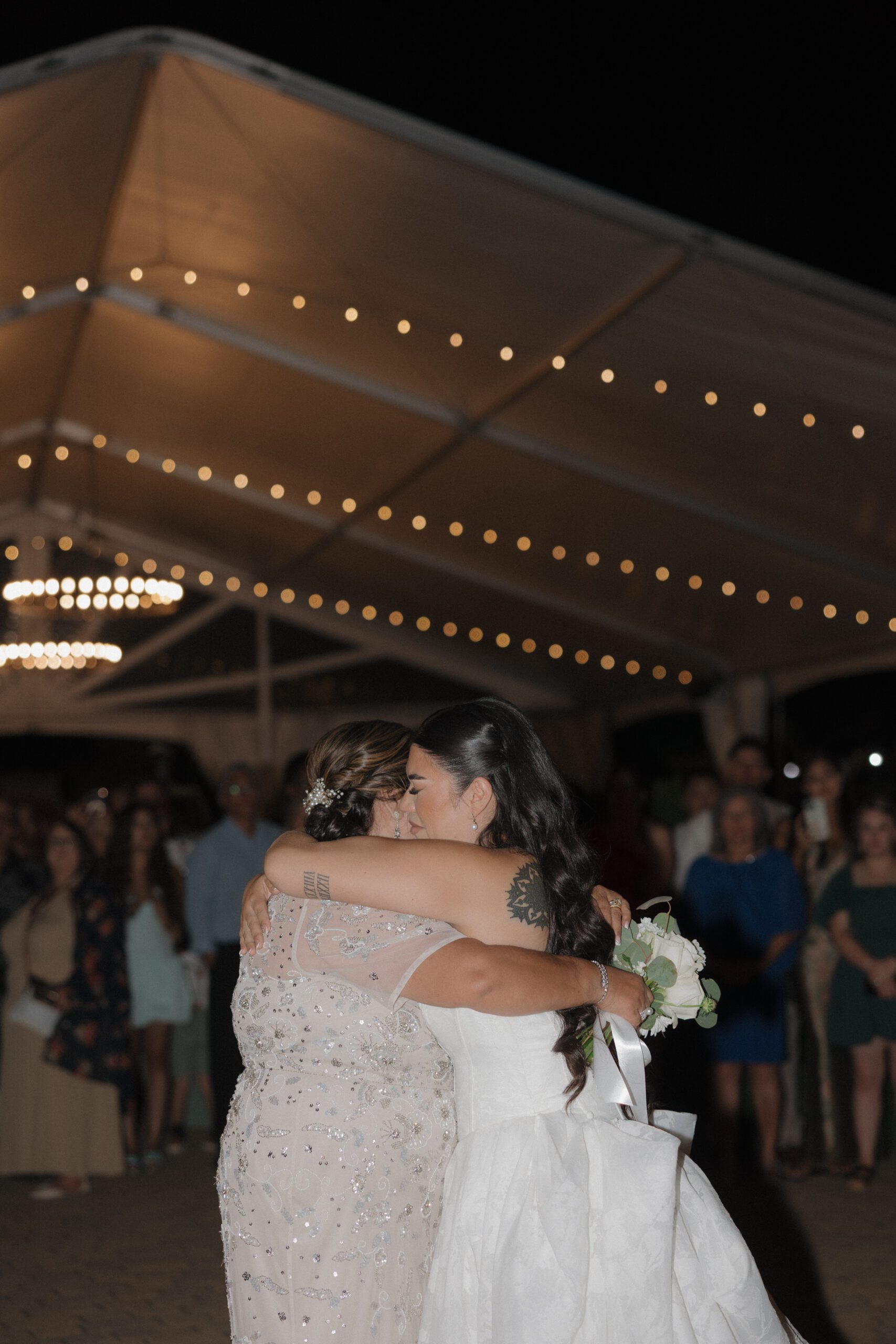 Emotional candid wedding photo of bride and her mother hugging