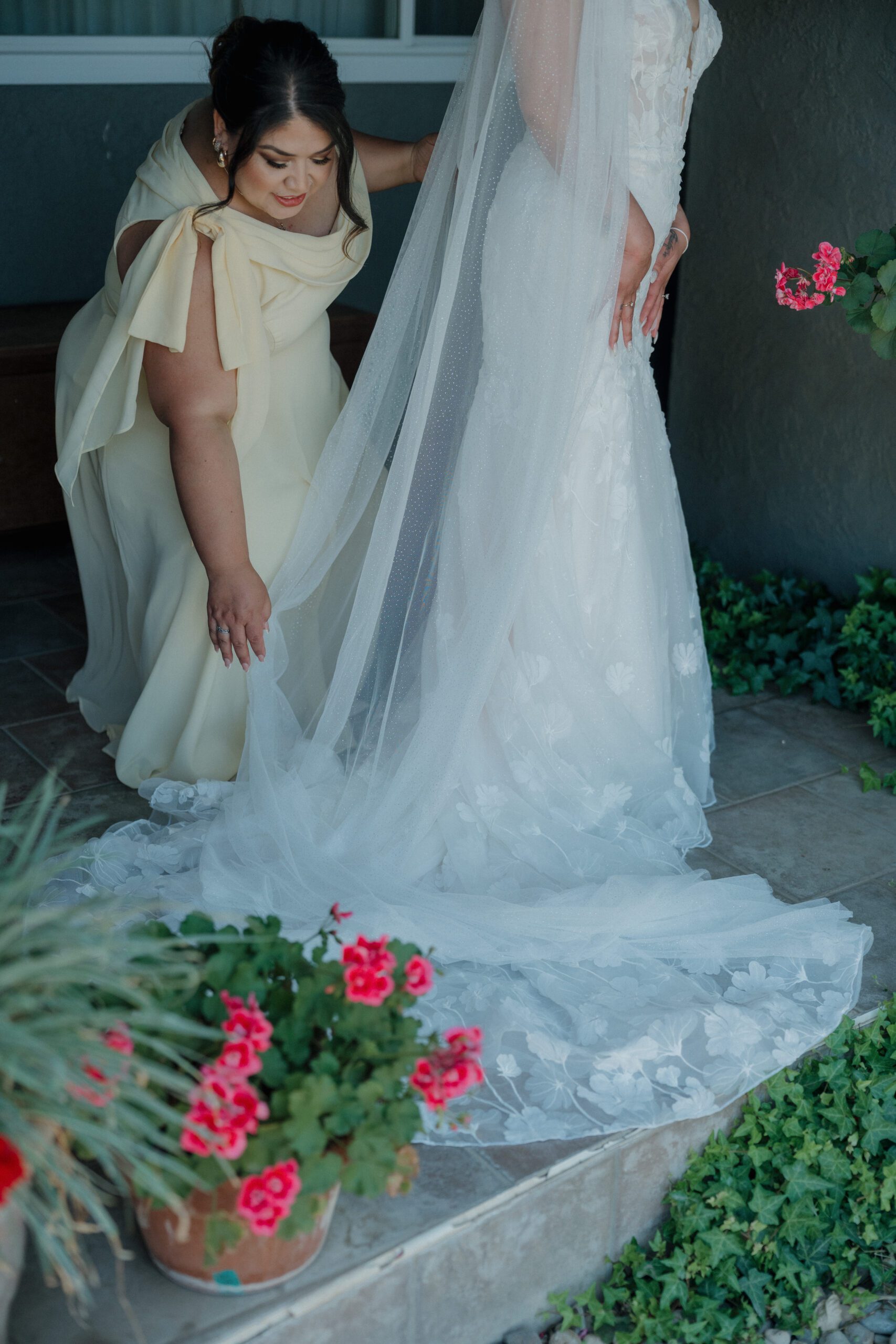 Mother of the bride helping her put on her wedding veil