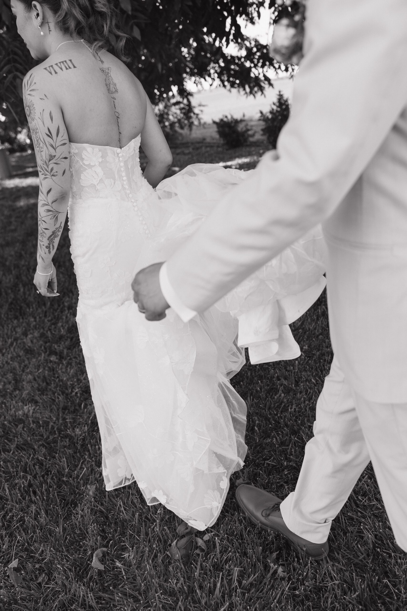 A groom carrying a bride's wedding dress train