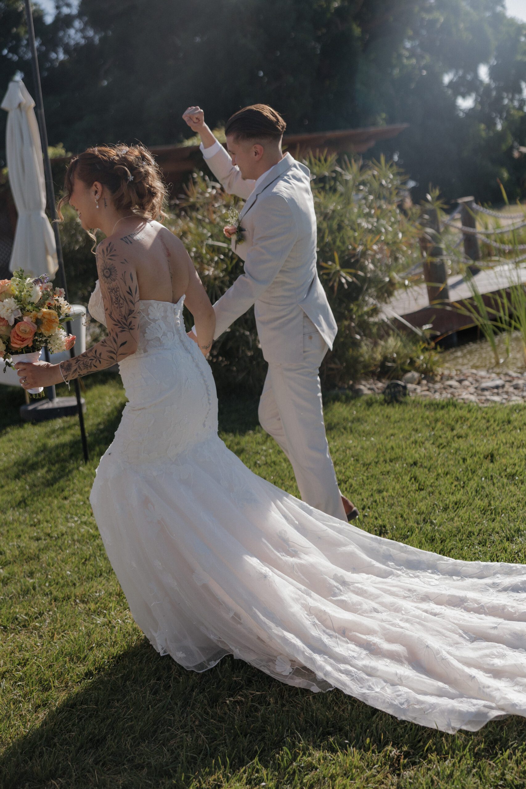 Bride and groom cheering while walking into their outdoor wedding reception