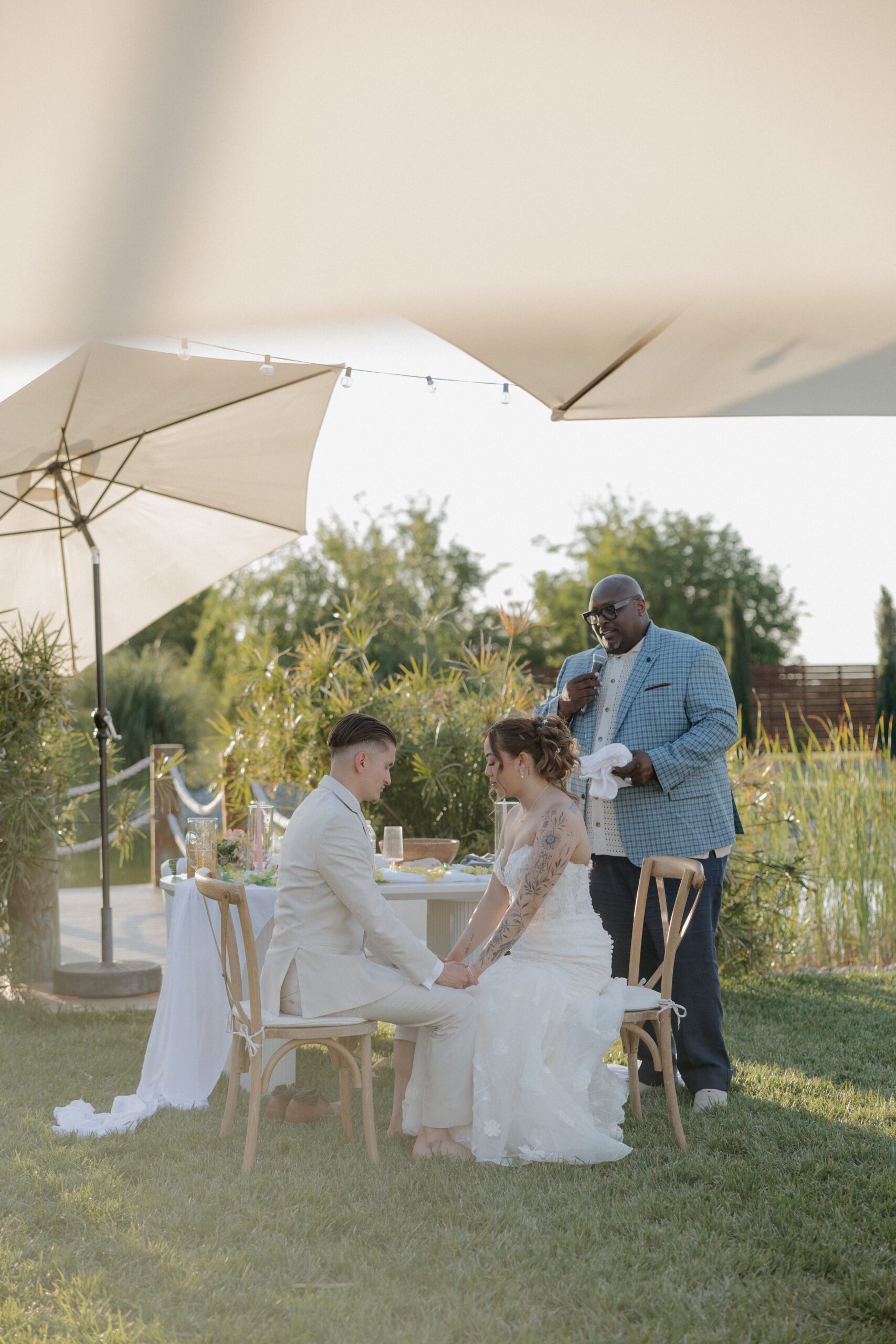 A bride and groom being prayed over at their outdoor wedding reception