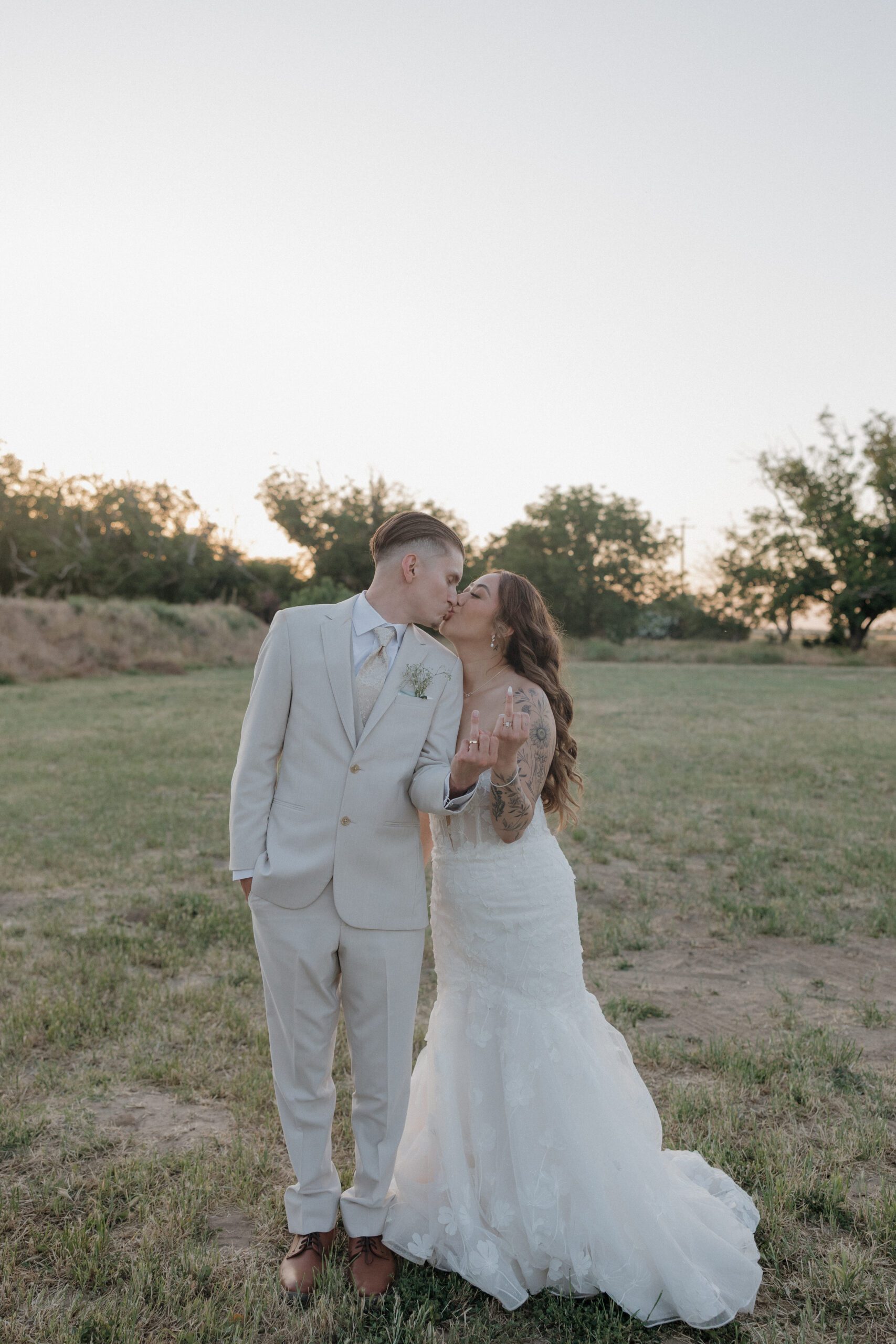 Bride and groom kissing and showing off their wedding rings
