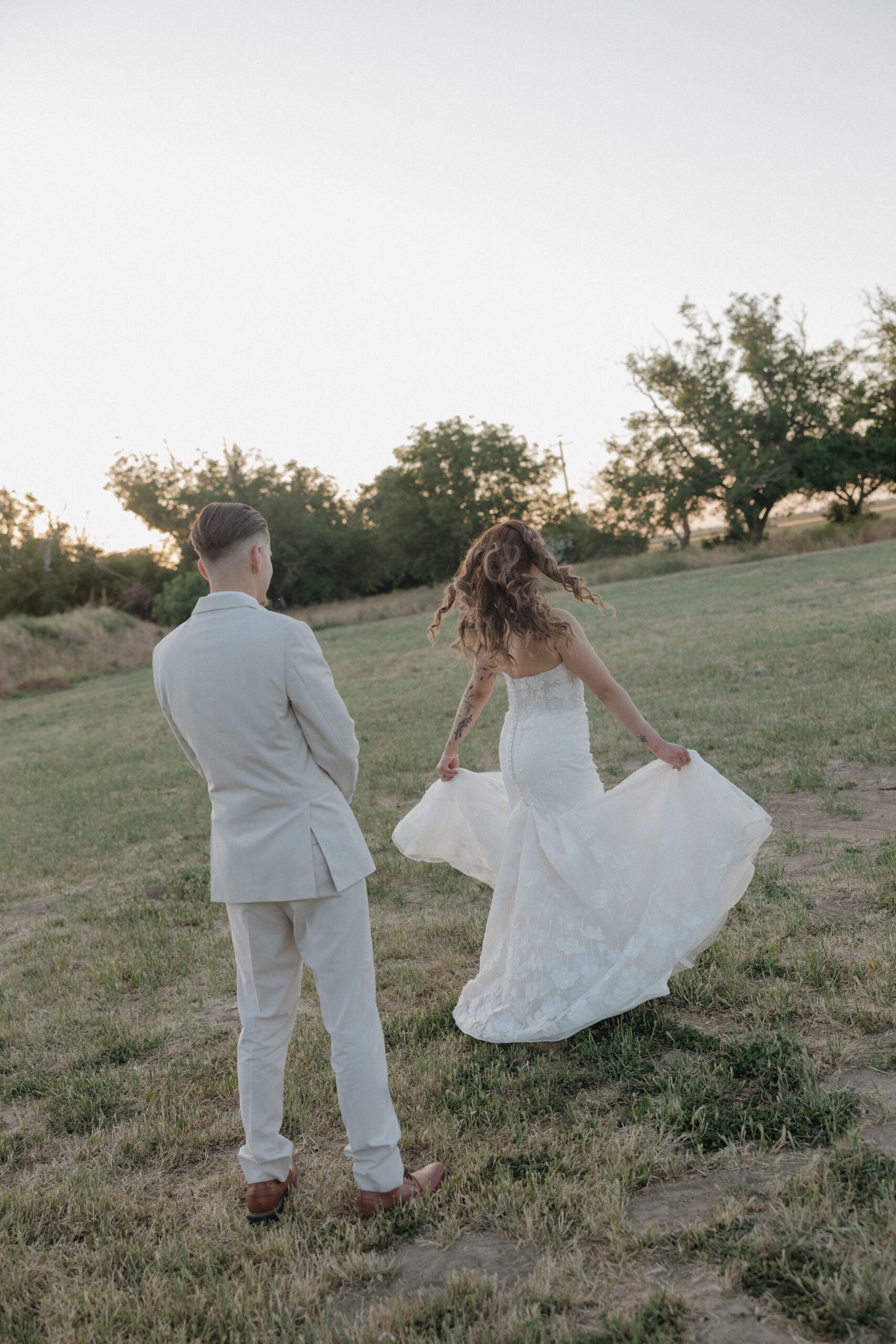 A groom watching a bride spin in her wedding dress