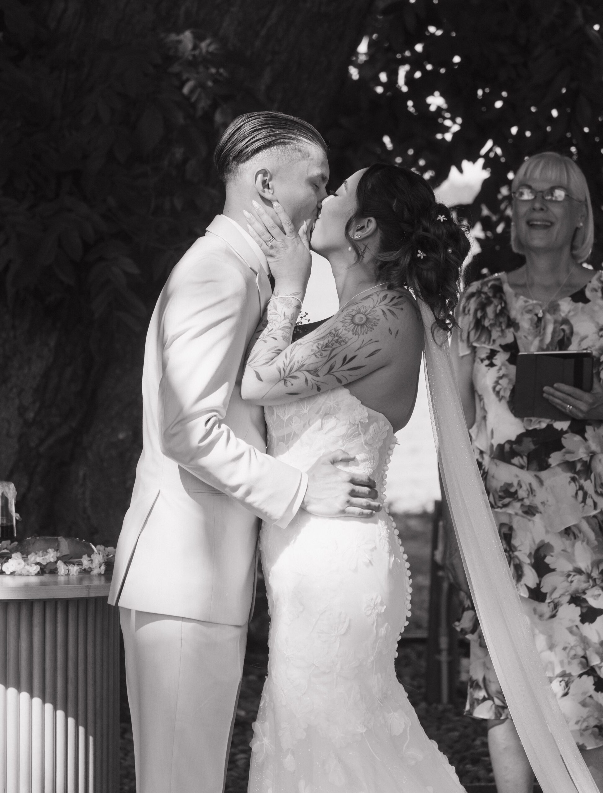 Bride and groom sharing first kiss at their outdoor wedding ceremony