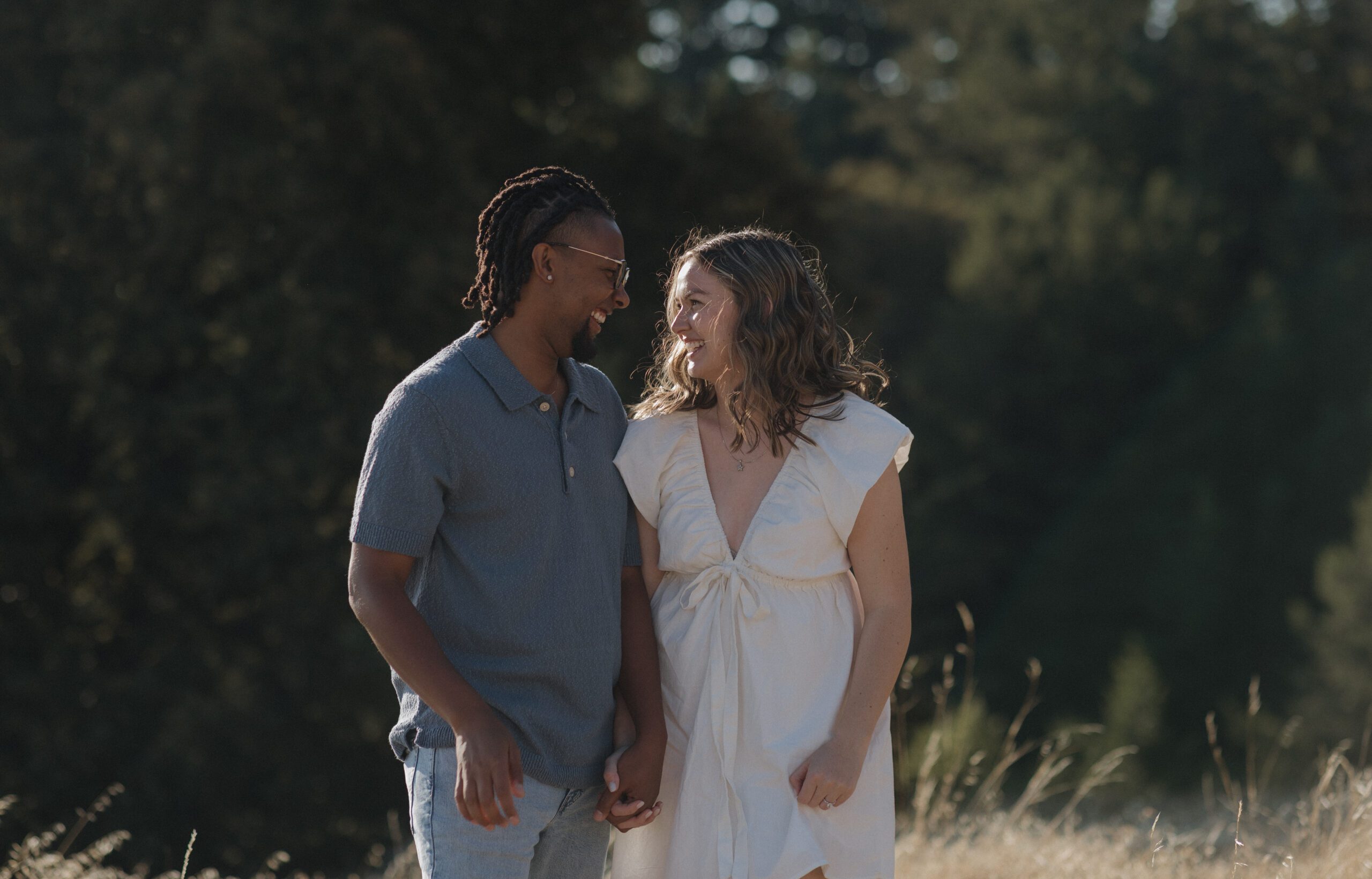 A couple holding hands and laughing at each other during their engagement photos