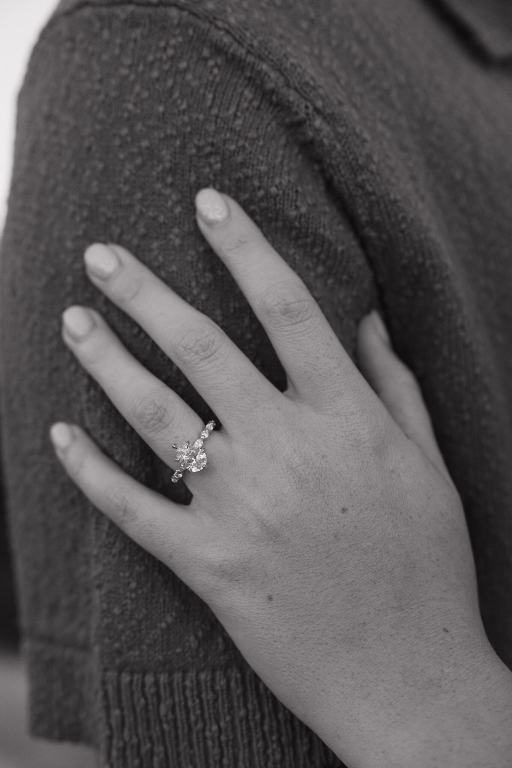 A black and white up-close photo of an oval engagement ring