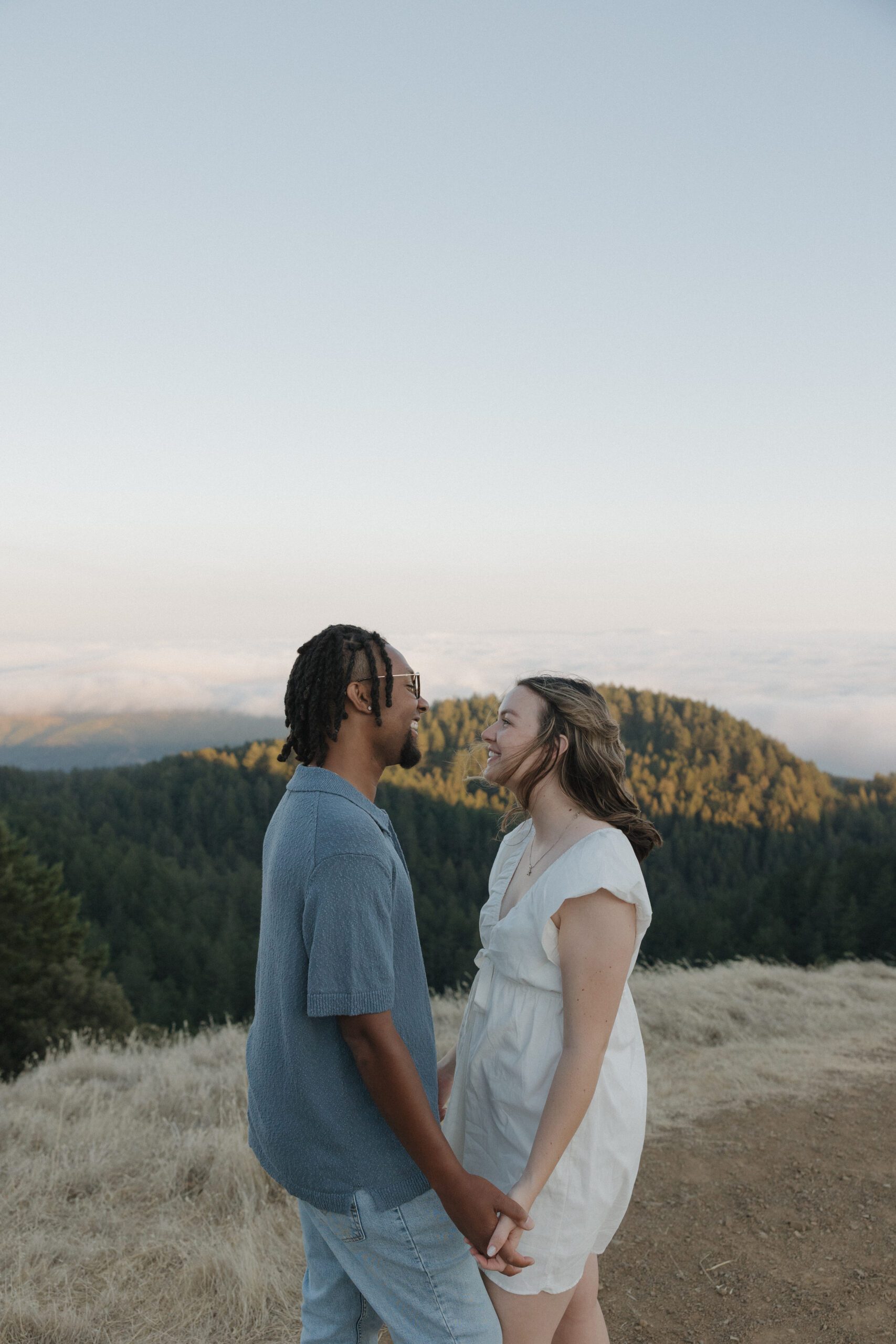 A couple smiling at each other in mountain engagement photos