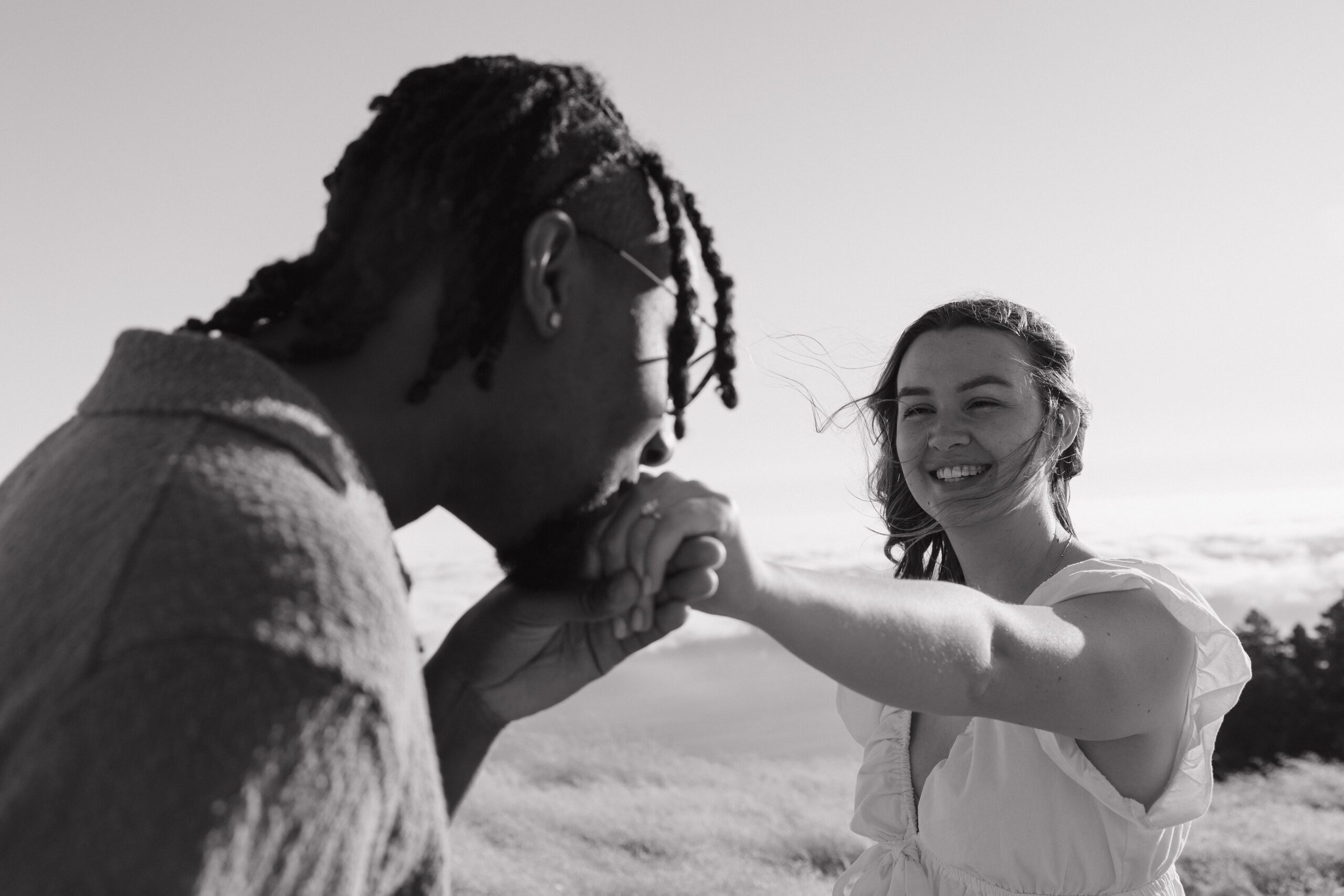 A man kissing his fiancee on the hand during their engagement photoshoot