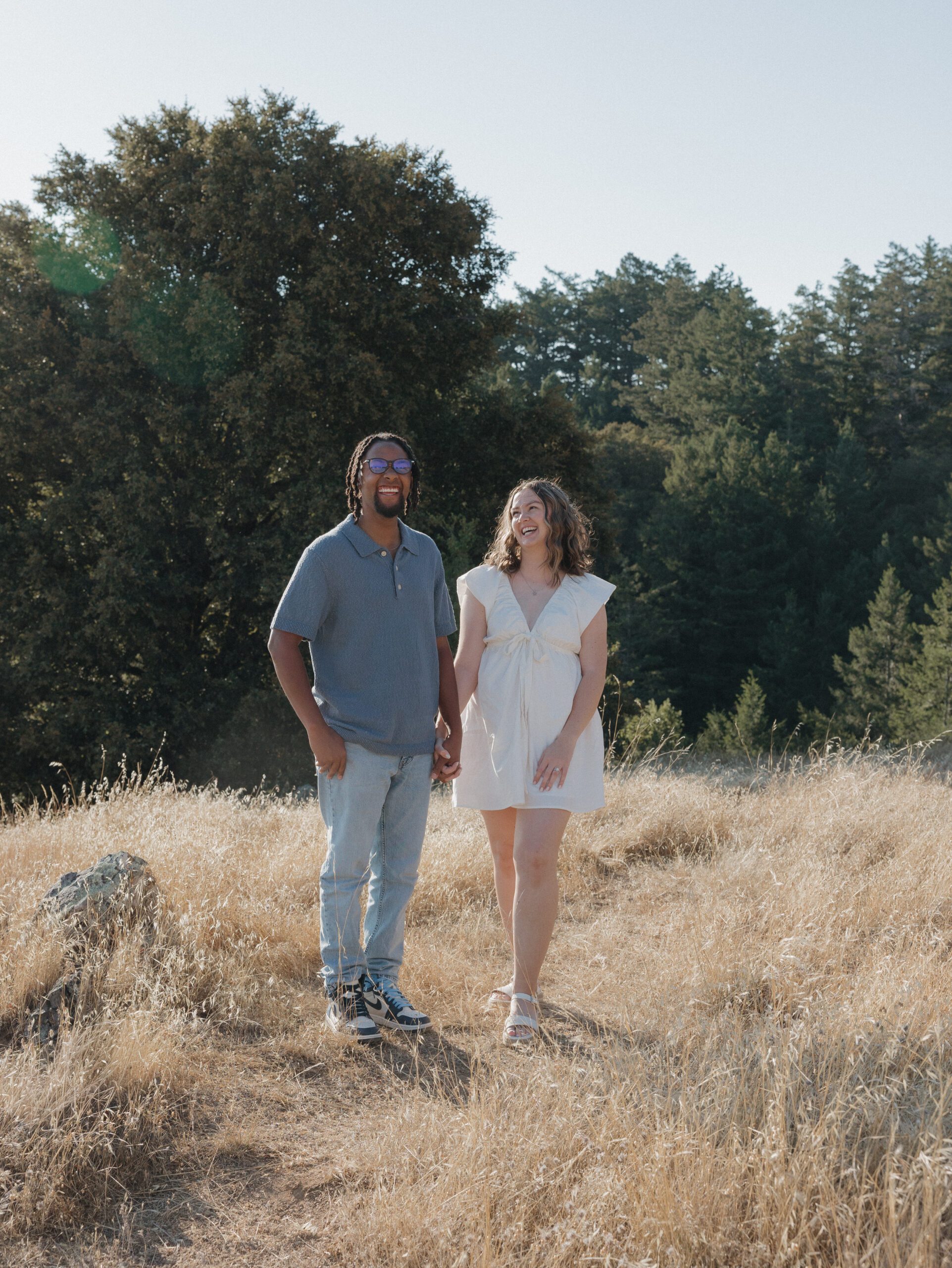 A couple laughing during their engagement photos in a field at Mt Tamalpais