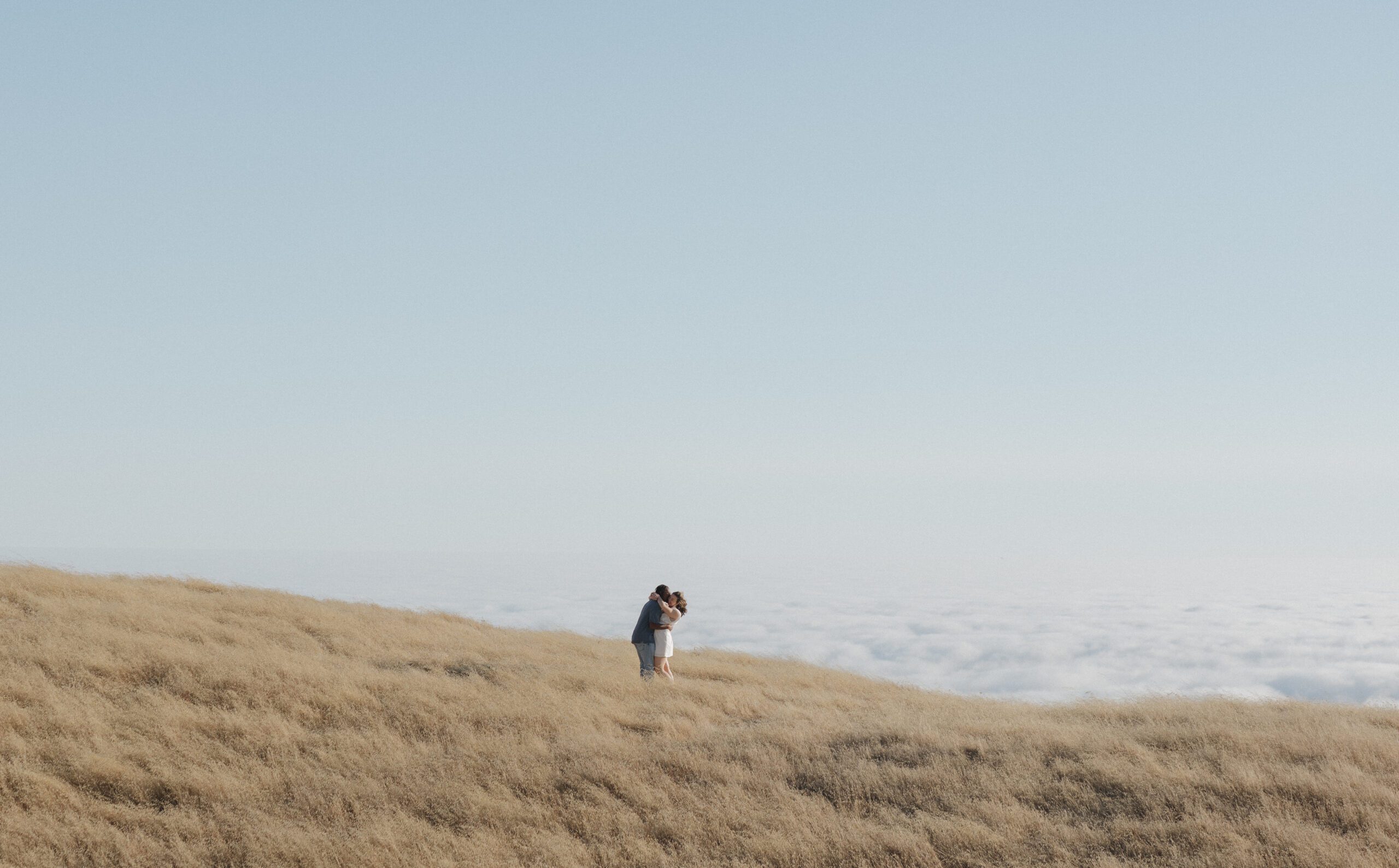 A photo of a couple hugging with the view from mt tamalpais behind them